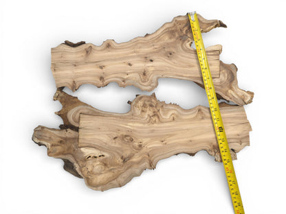 An overhead shot of two irregular wood pieces, their combined length indicated by a tape measure.