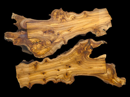 Two irregularly shaped wood pieces displaying prominent, wavy grain patterns against a solid black background.