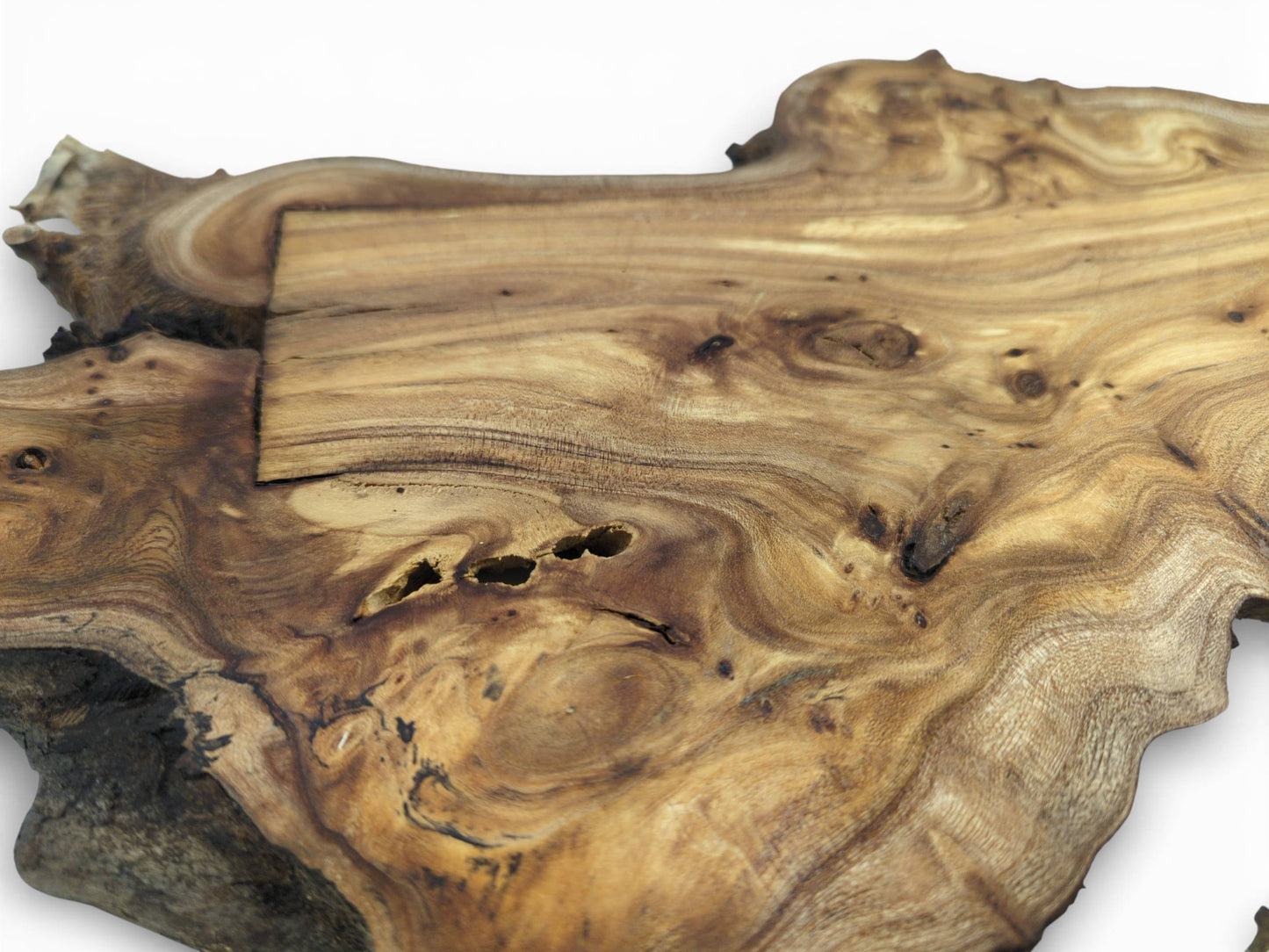 High-angle shot of a hardwood slab featuring complex wood grain, natural holes, and a rectangular patch.