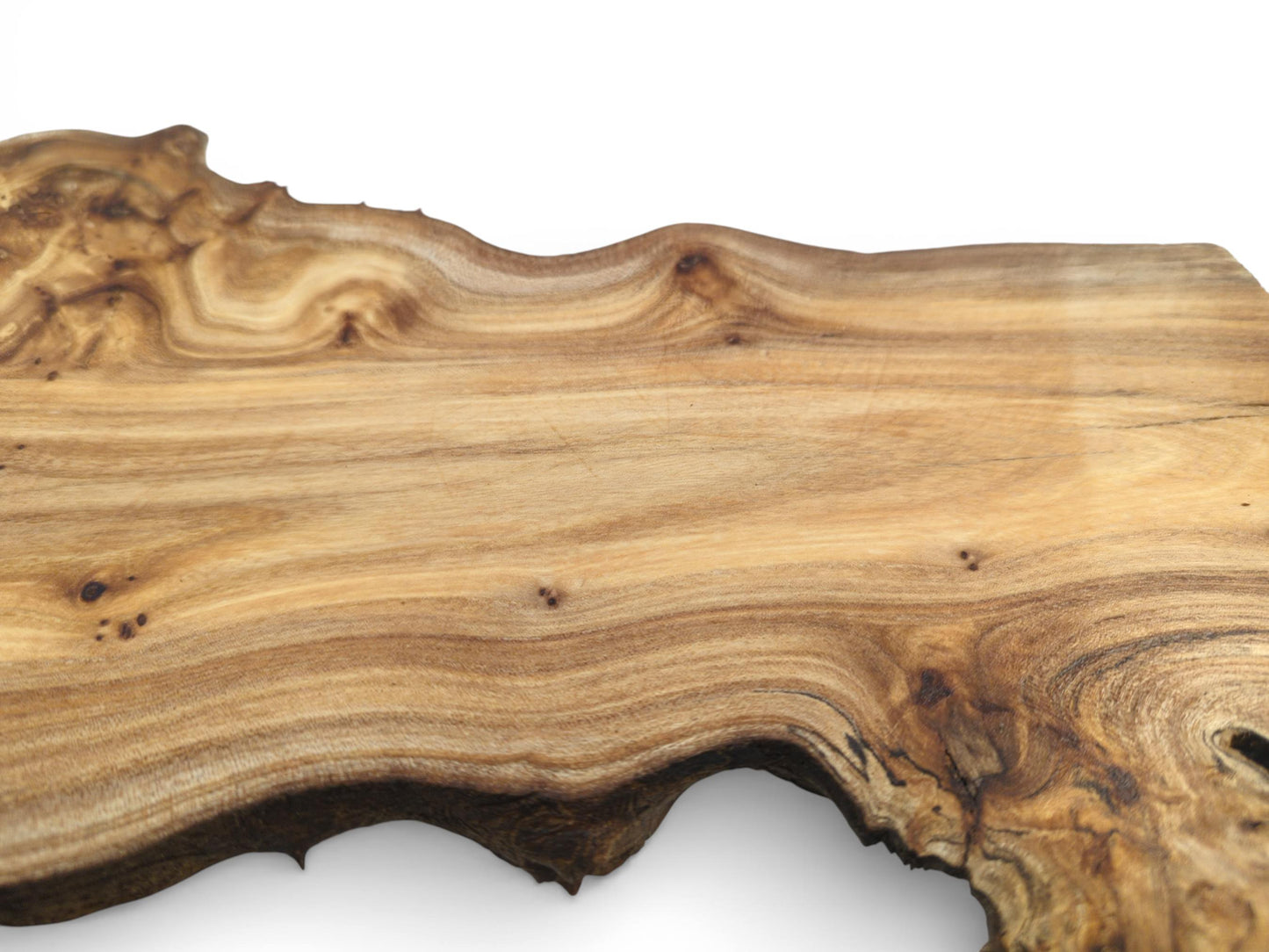 A wood slab with a smooth surface and flowing grain, seen from a close, angled perspective.