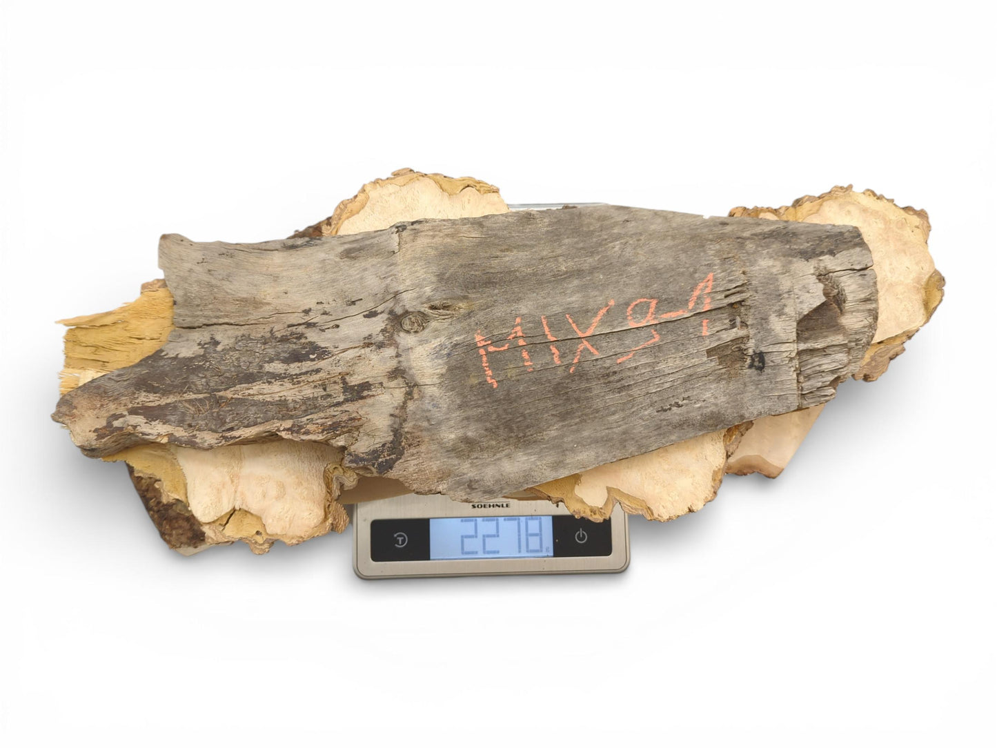 A collection of raw, irregular wood pieces placed on a small digital scale showing their weight.