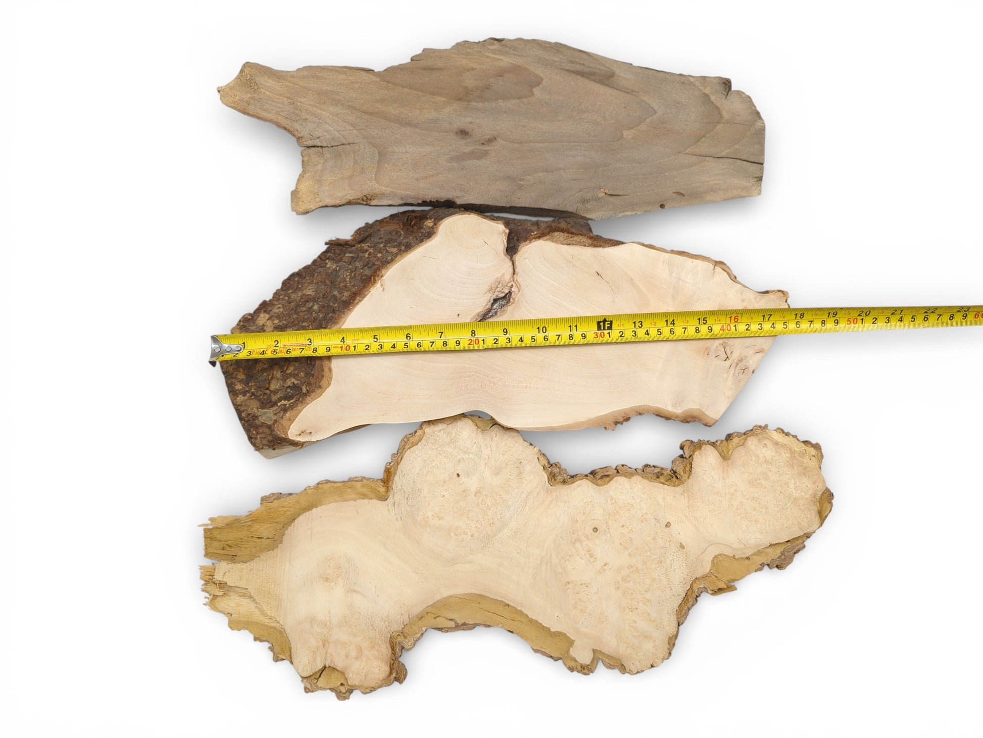 Overhead view of three assorted wood slabs, with a yellow tape measure laid across the middle piece.