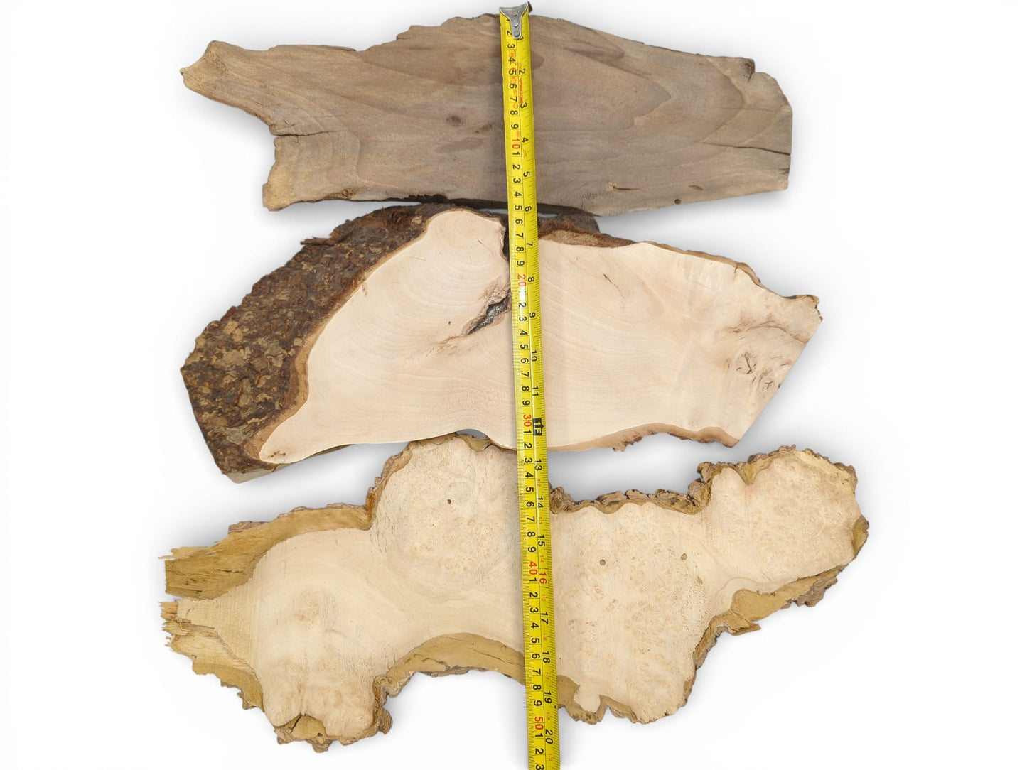 A vertical stack of three varied wood slabs with a yellow ruler measuring their combined length.