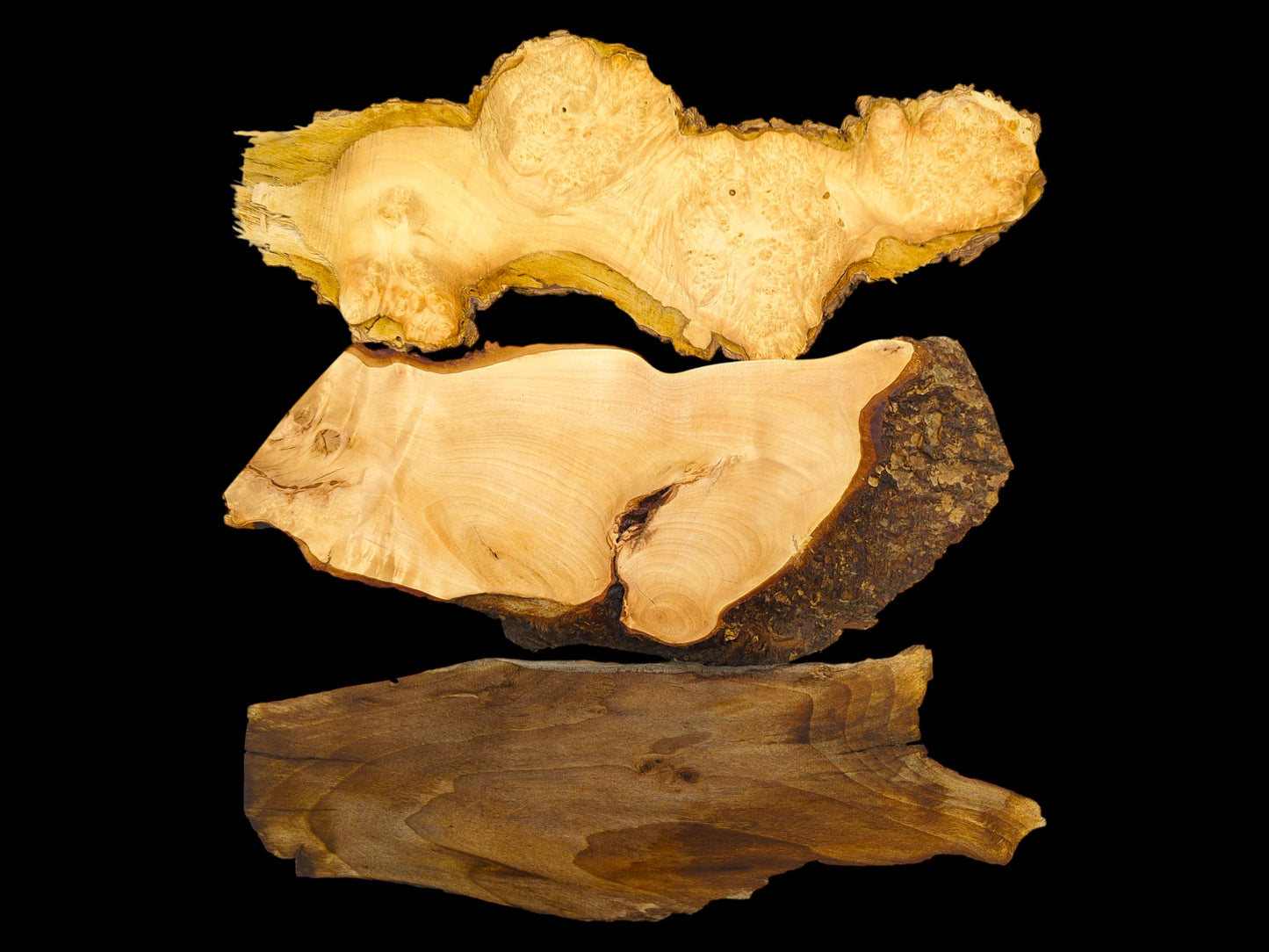 A direct comparison of three stacked wood slabs, showing varied grains, colors, and natural edges.