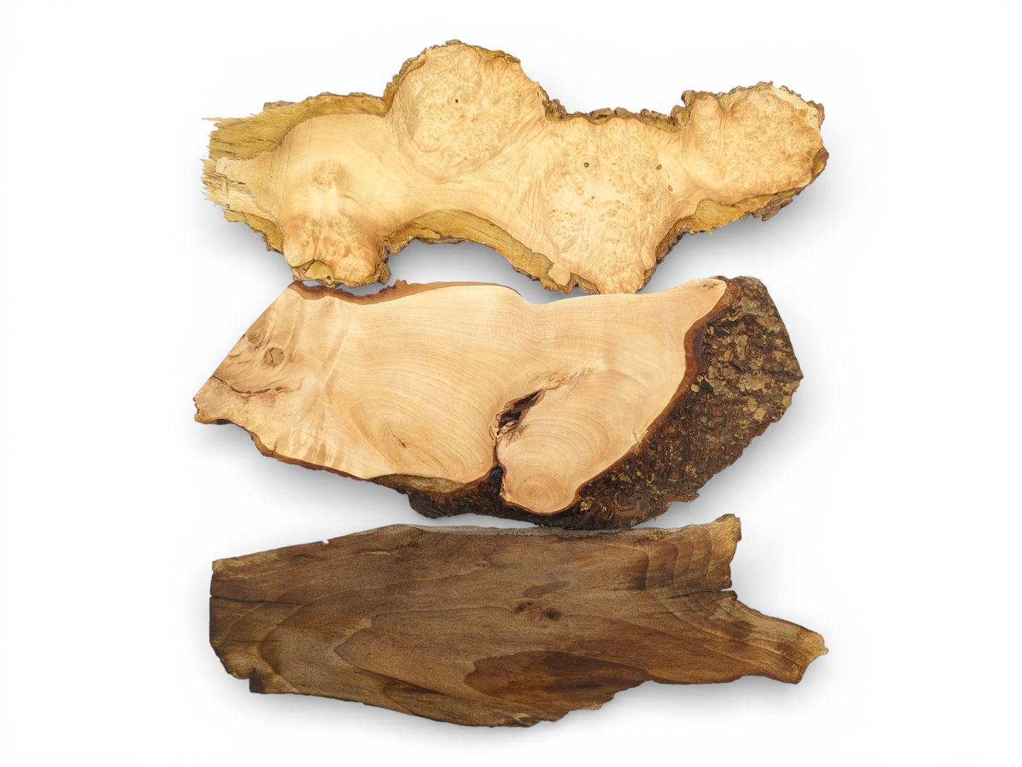 A direct overhead view of three distinct wood slabs: light burl, pale with bark, and dark walnut.
