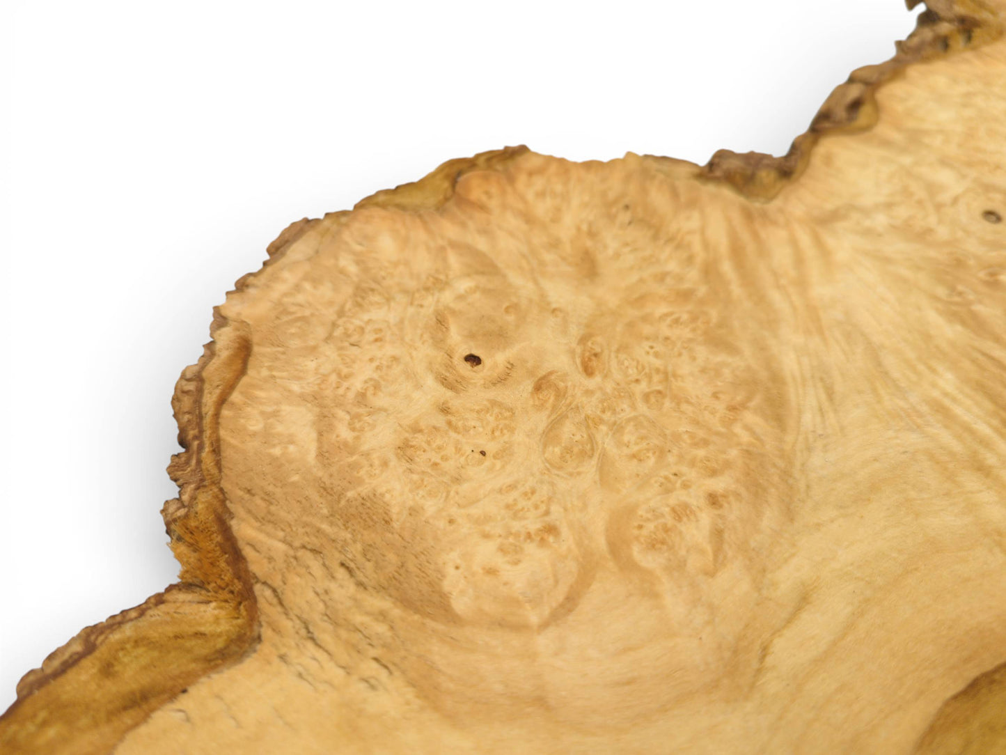 A close-up view of a light wood slab's surface, showing its intricate burl pattern and live edge.