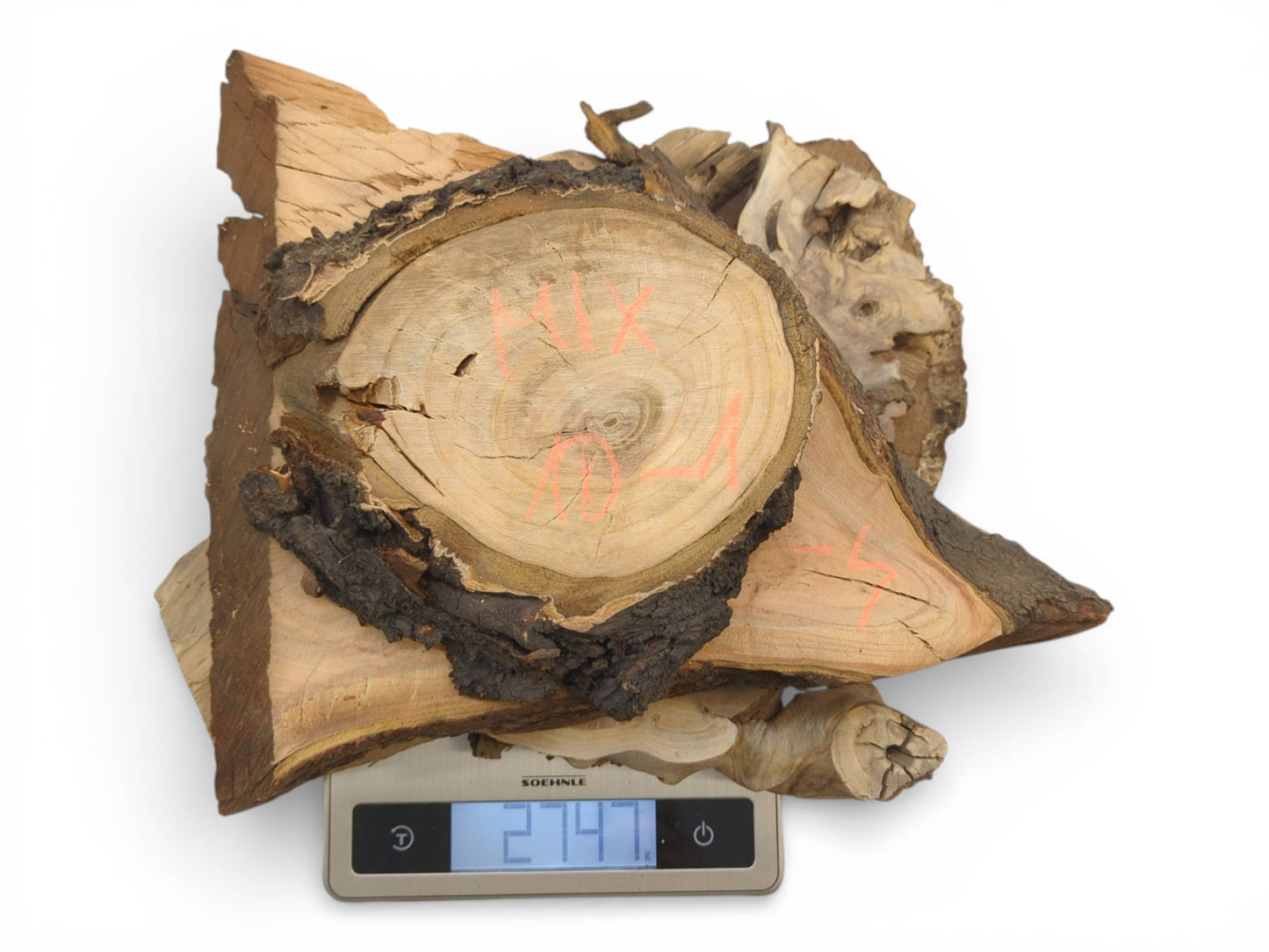 A collection of raw-edge wood slices with dark bark sits on a scale showing its weight.