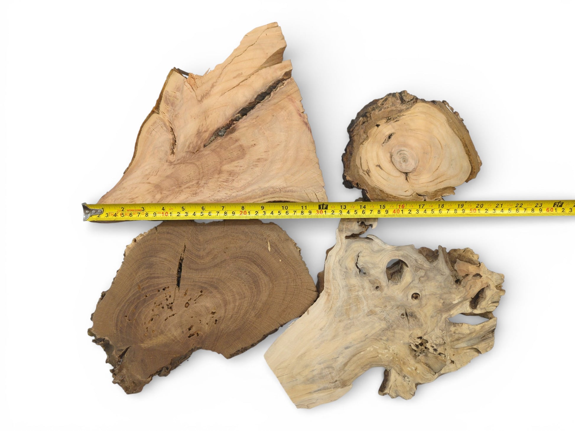 An overhead view of four distinct wood cuts, their dimensions indicated by a horizontal tape measure.