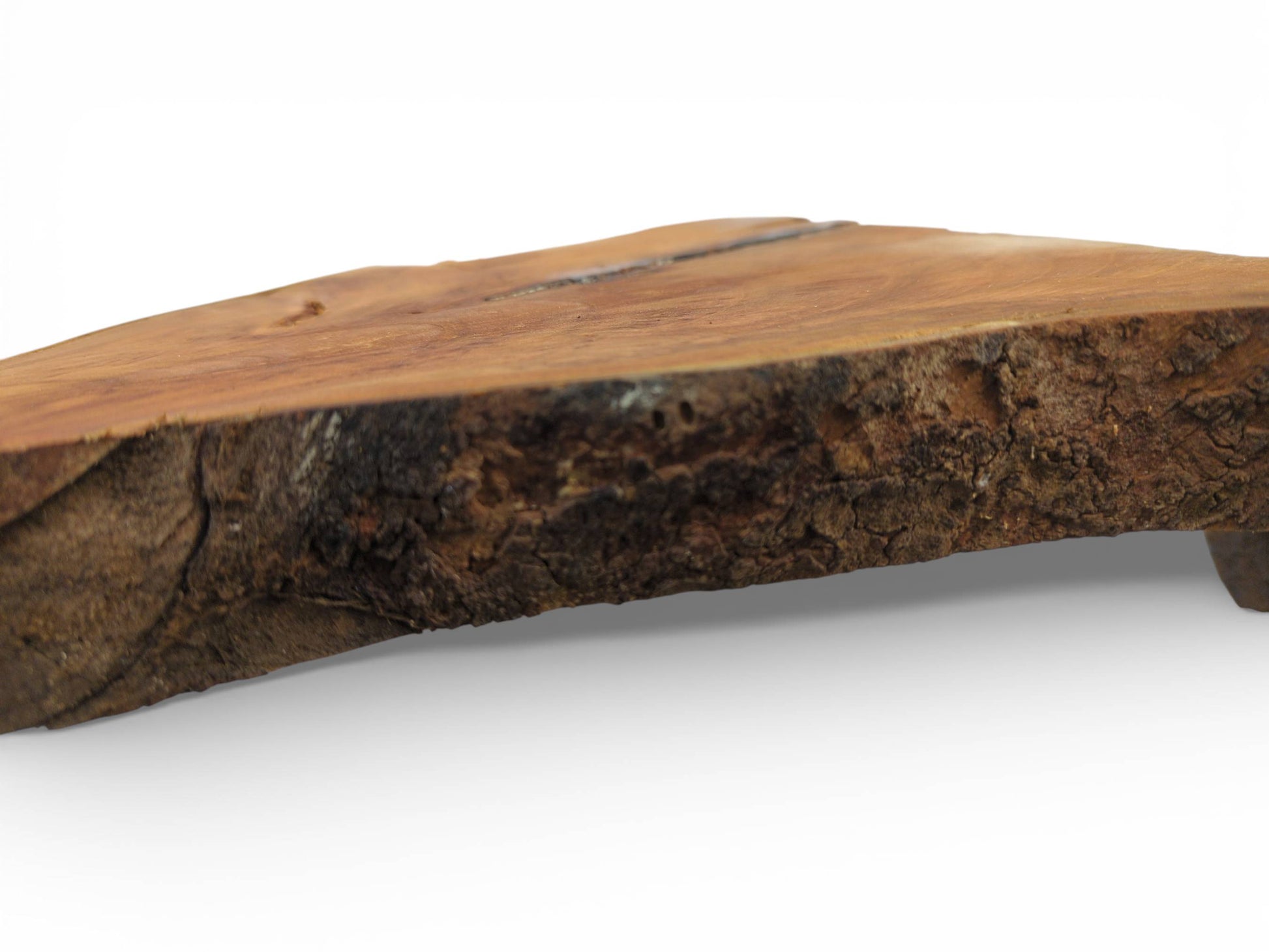 A profile view of a wood slab, focusing on the rough, dark bark below its smooth surface.