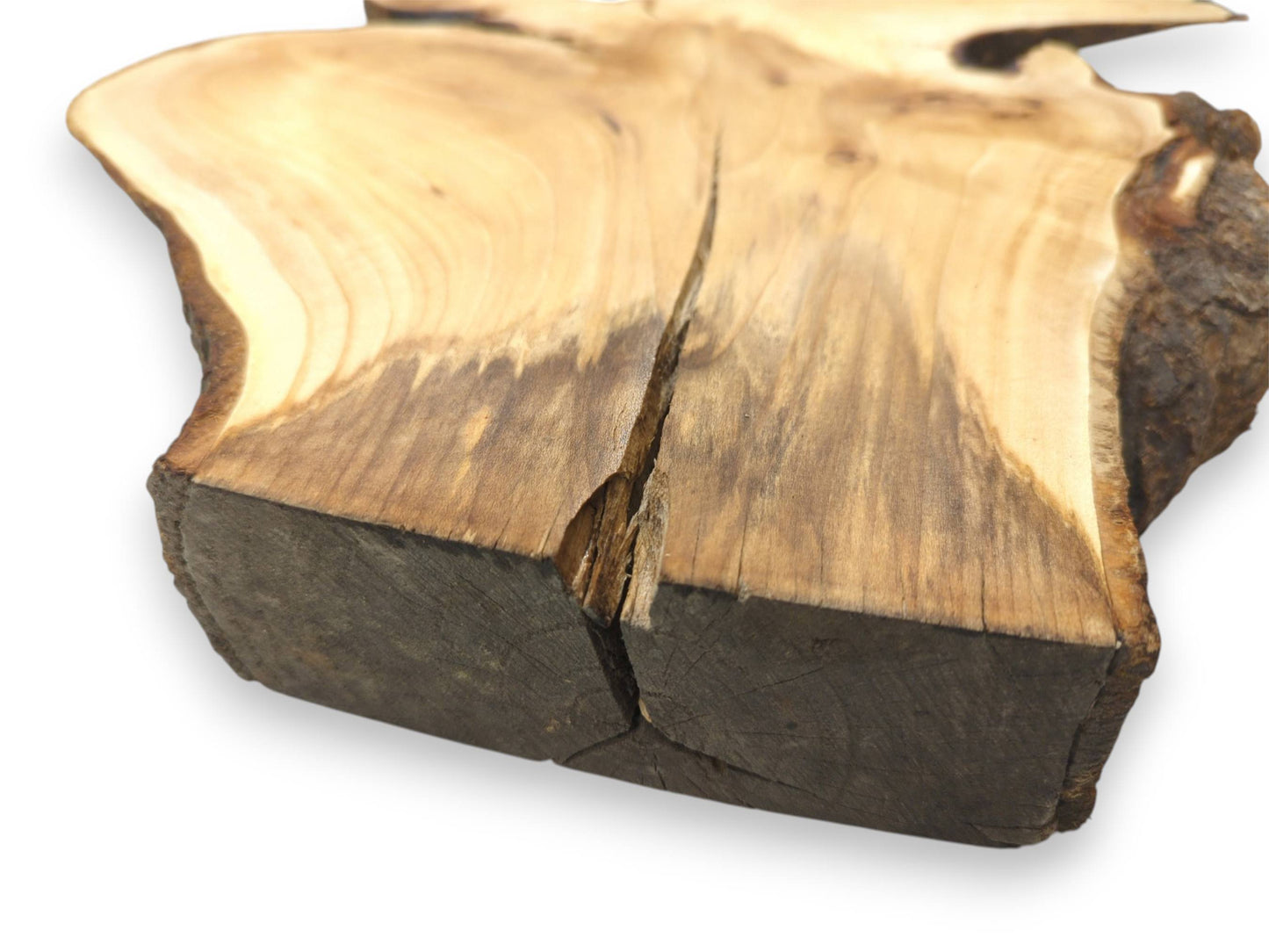A deep crack splits the dark, sawn end of a wood slab with stained grain.
