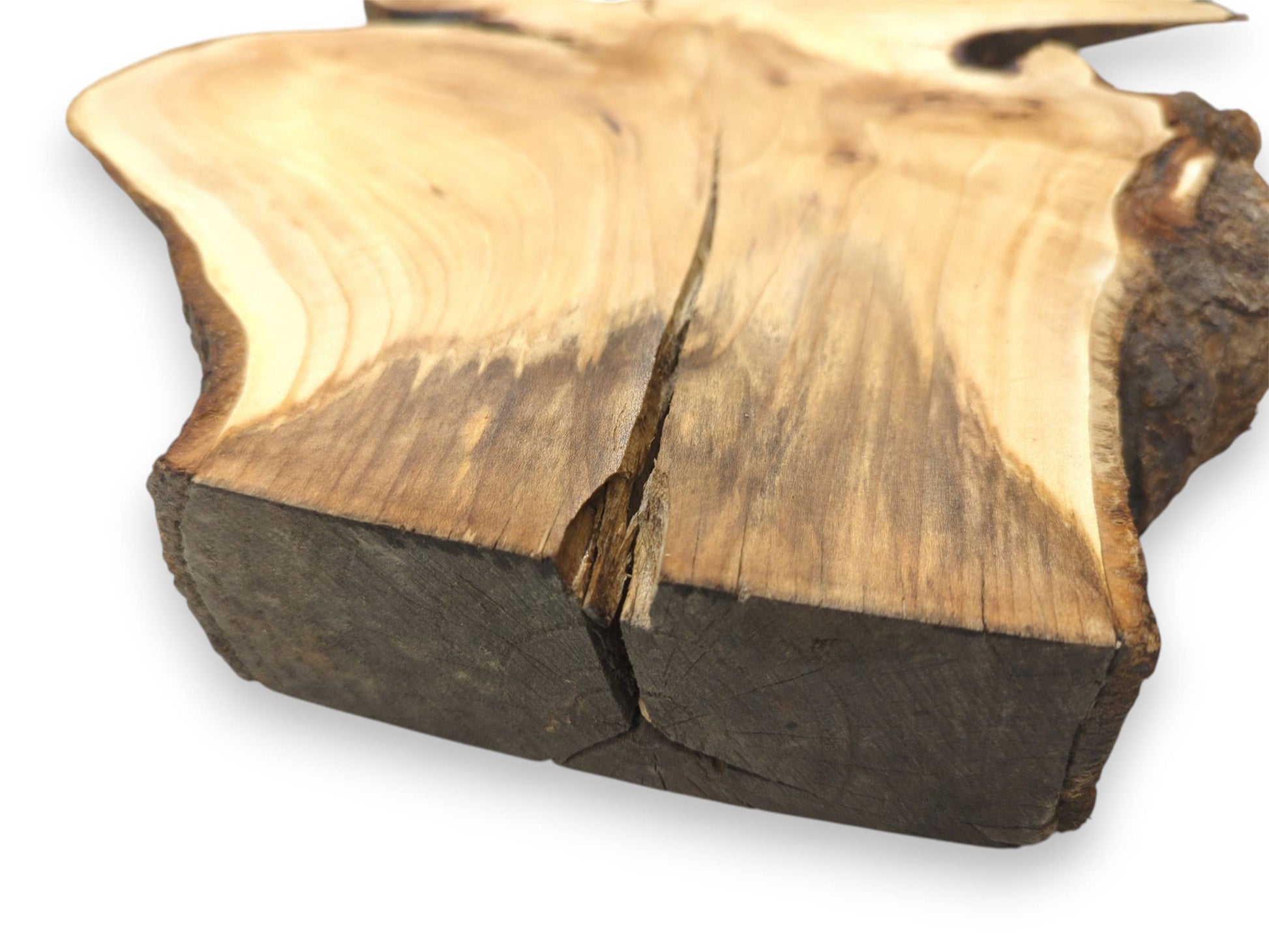 A deep crack splits the dark, sawn end of a wood slab with stained grain.