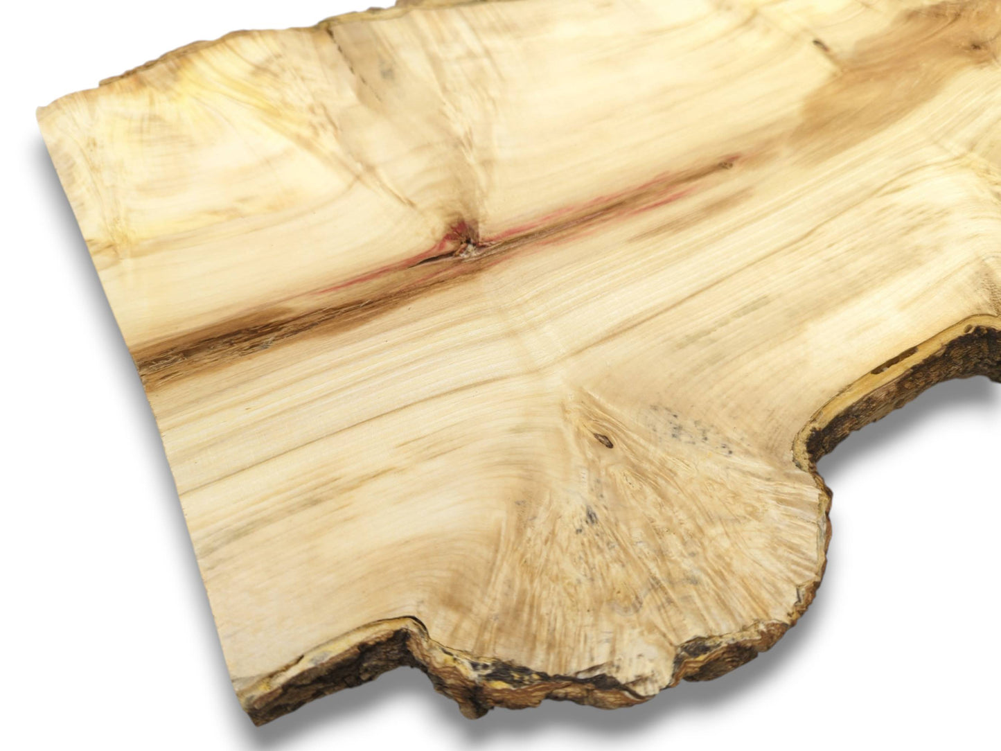 A diagonal red mineral streak bisects the fanning grain of a pale wood slab.