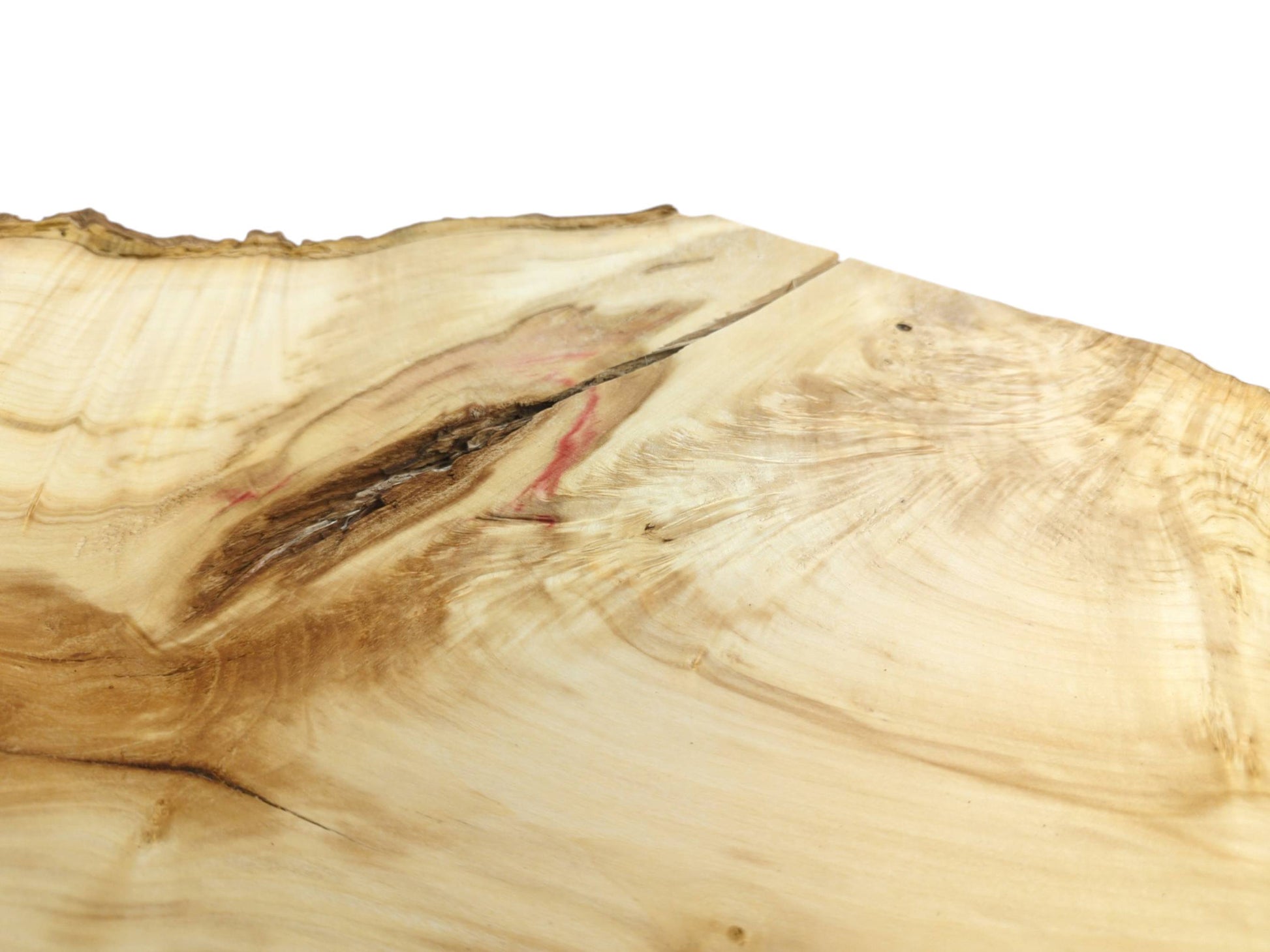 A dark, rugged fissure with red mineral accents splits the pale surface of a timber slab.