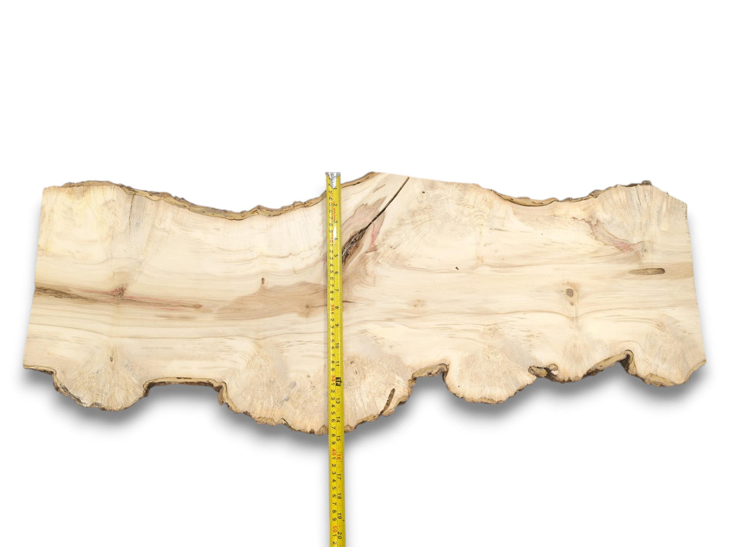 A yellow tape measure bisects a wide, pale timber slab with an undulating live edge.