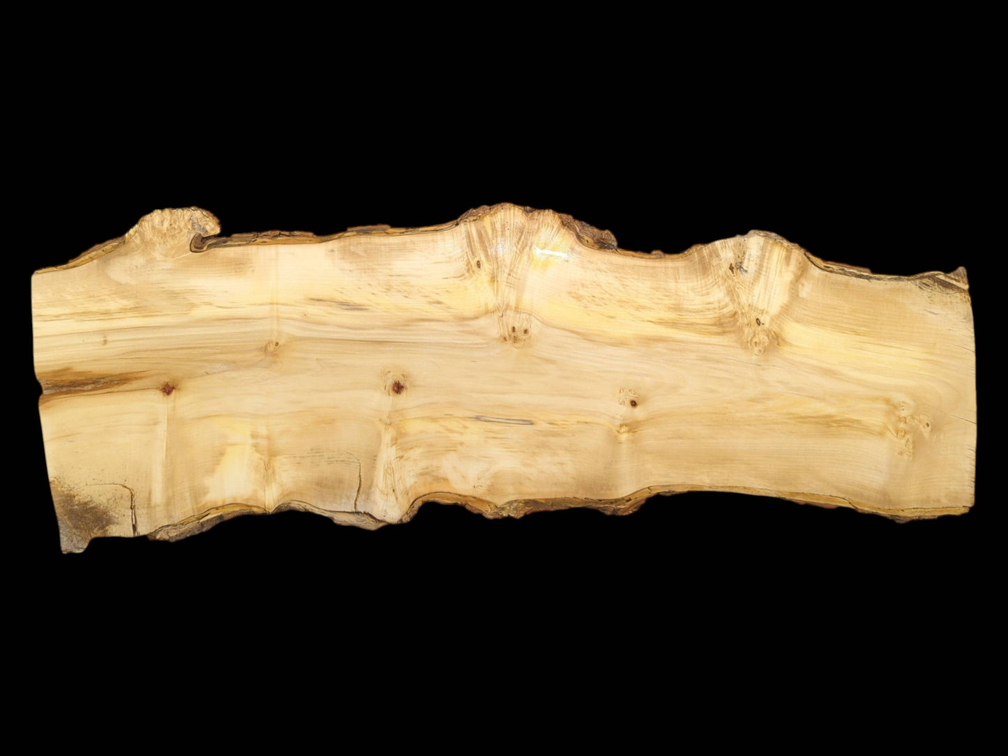 A long, pale lumber slab with a flowing grain and a wavy, bark-lined top edge.