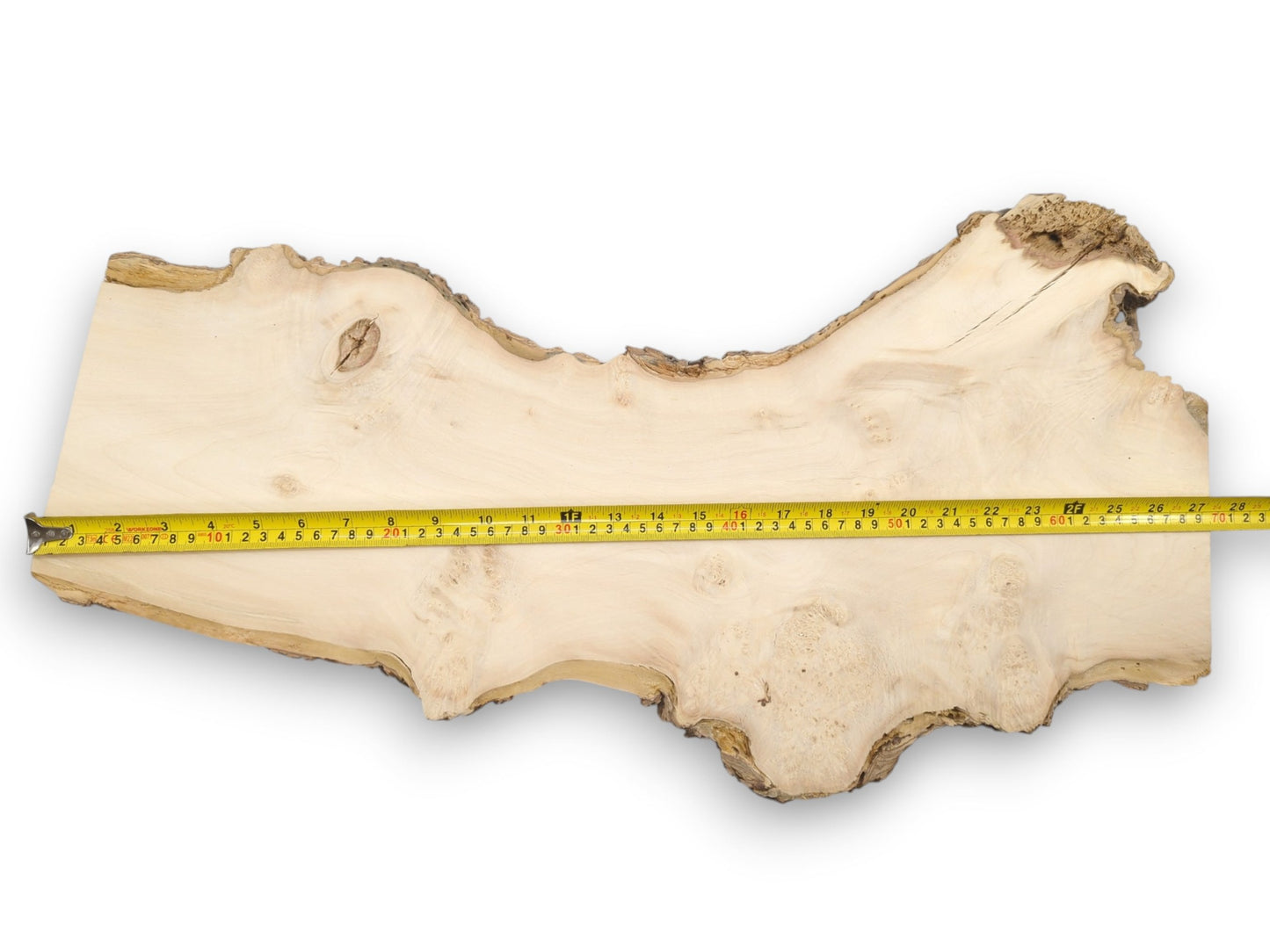 A yellow tape measures a long, pale wood slab with a single cross-shaped knot.