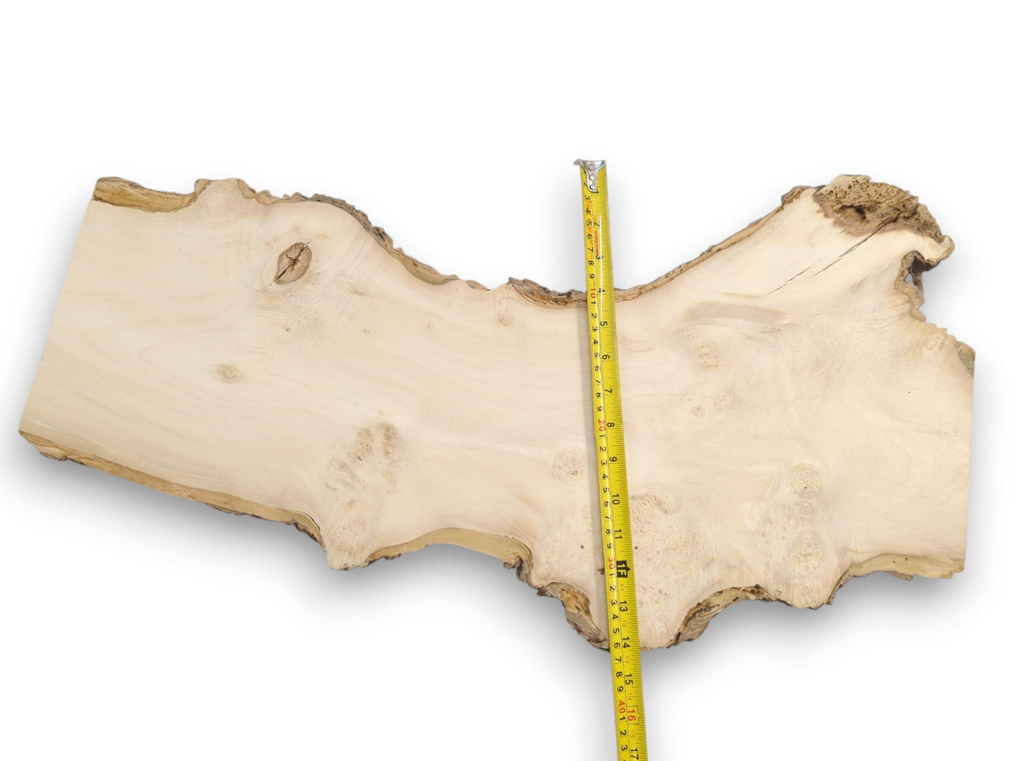Overhead view of a yellow tape measure crossing an irregular, light-colored wood plank.