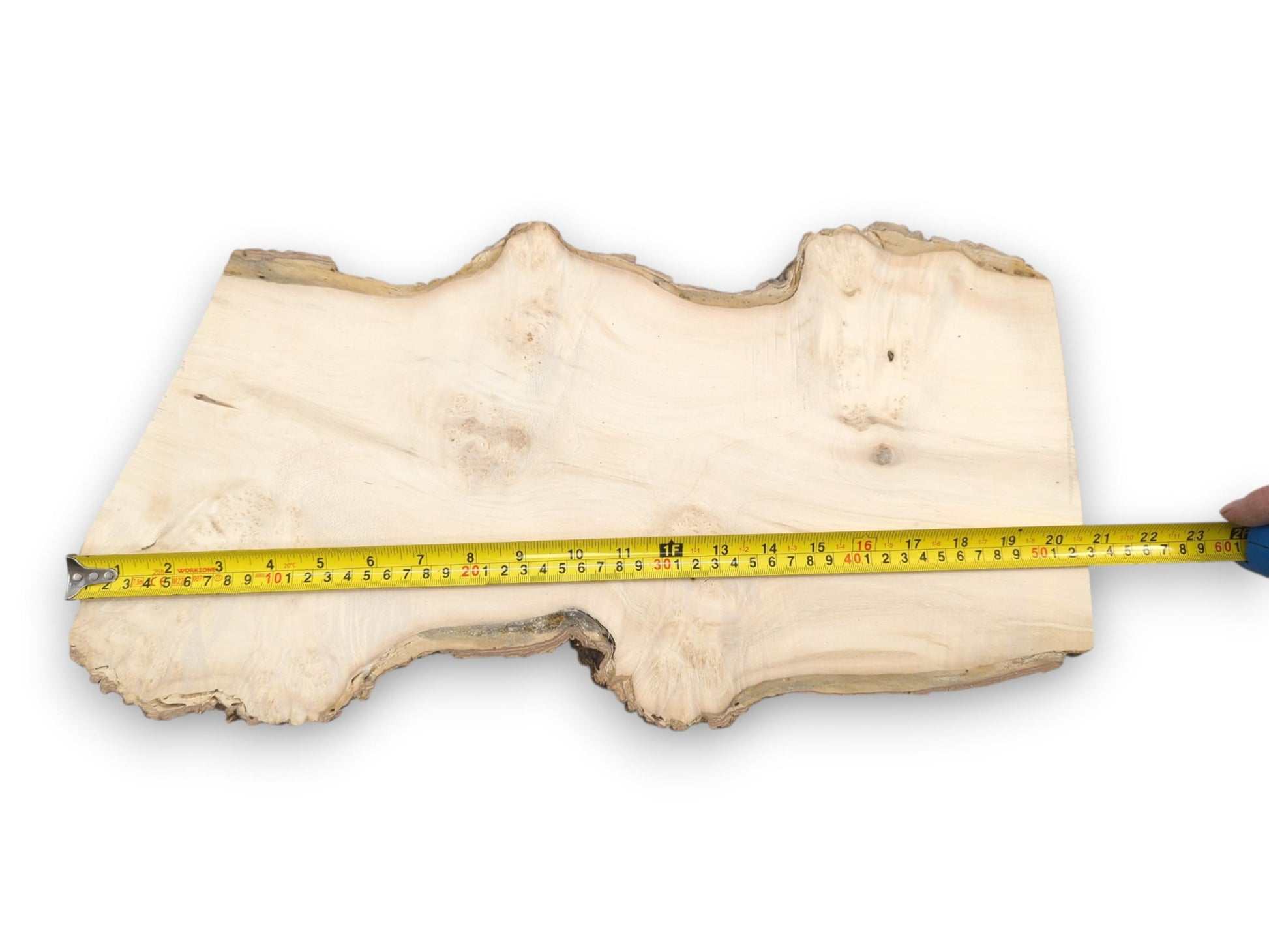 A measuring tape is laid across a pale timber plank with a wavy, natural perimeter.