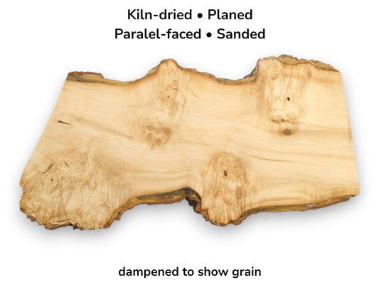Overhead view of a light-colored lumber slab with a dark, undulating live edge and burl eyes.