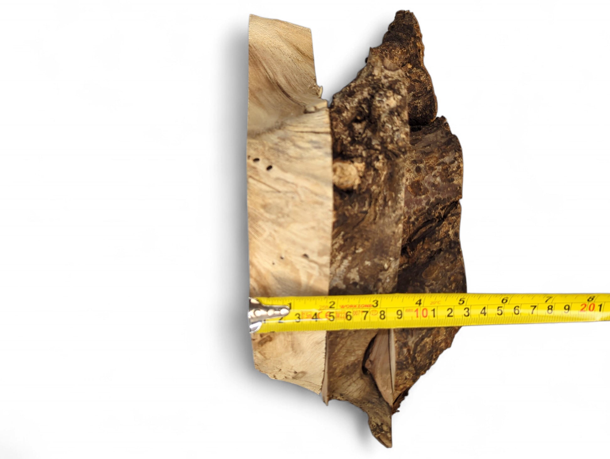 Yellow measuring tape across an irregular wood slice with a light sanded face and dark bark edge.