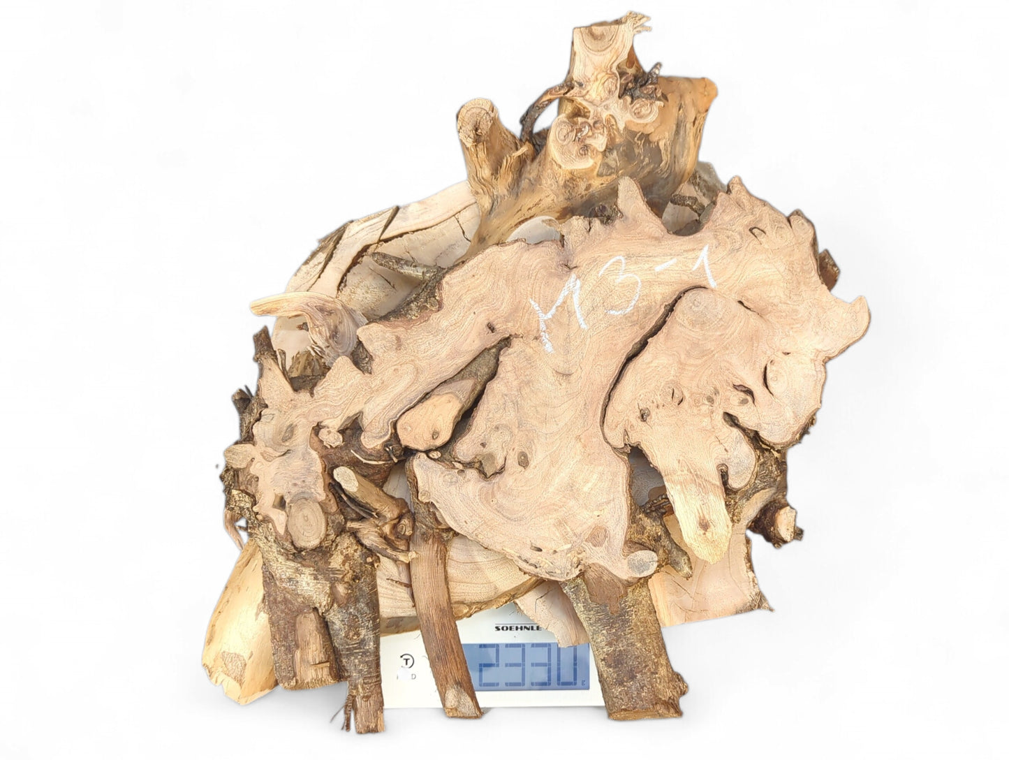 Irregular light brown and dark raw wood pieces, one marked M3-1, are stacked on a scale displaying 2330.