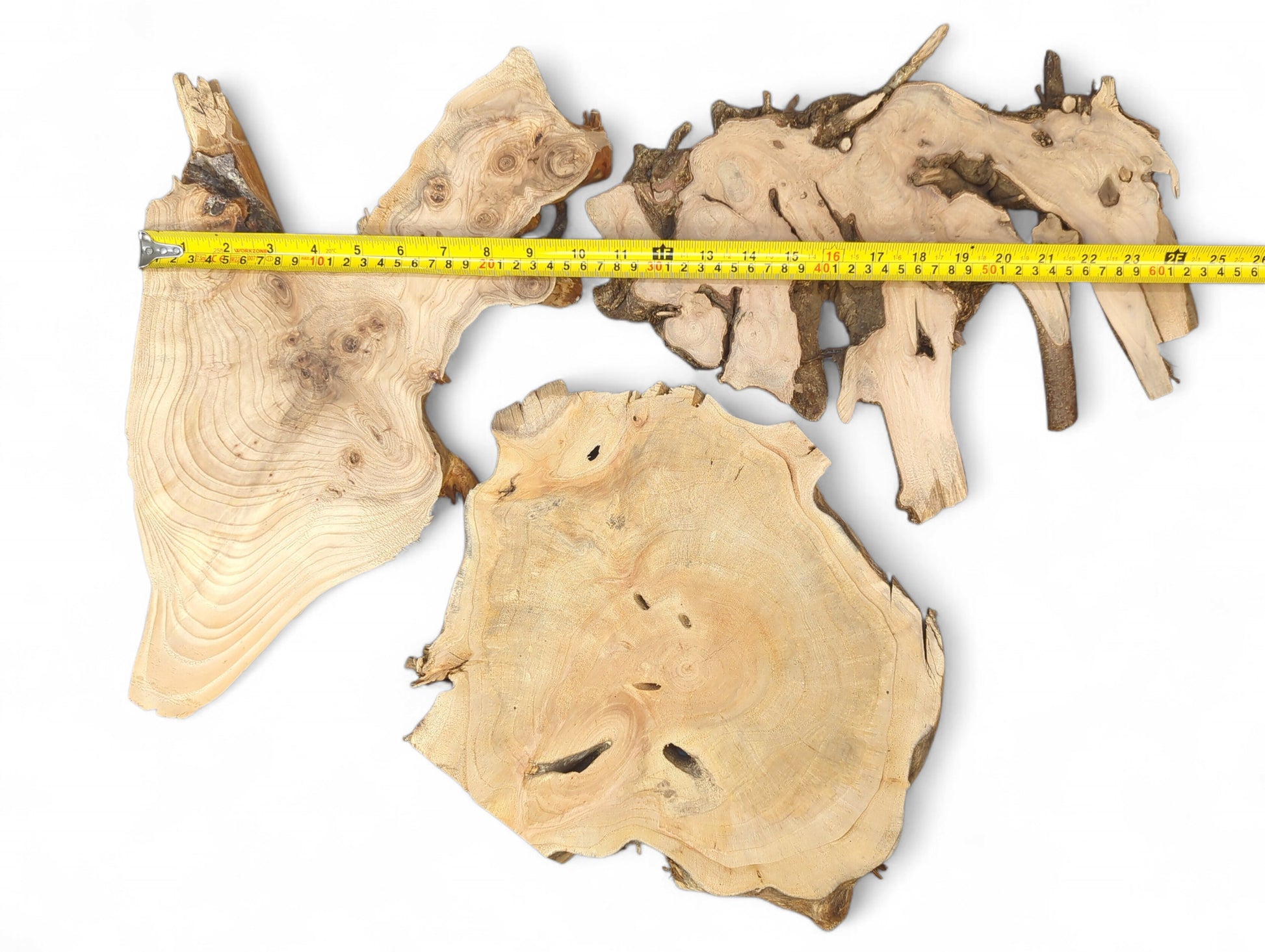 A yellow measuring tape overlays three light-colored, irregular raw wood pieces with natural edges on white.