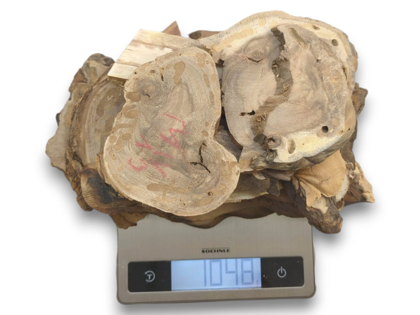 A pile of assorted small, light brown wood pieces with natural edges on a digital scale.