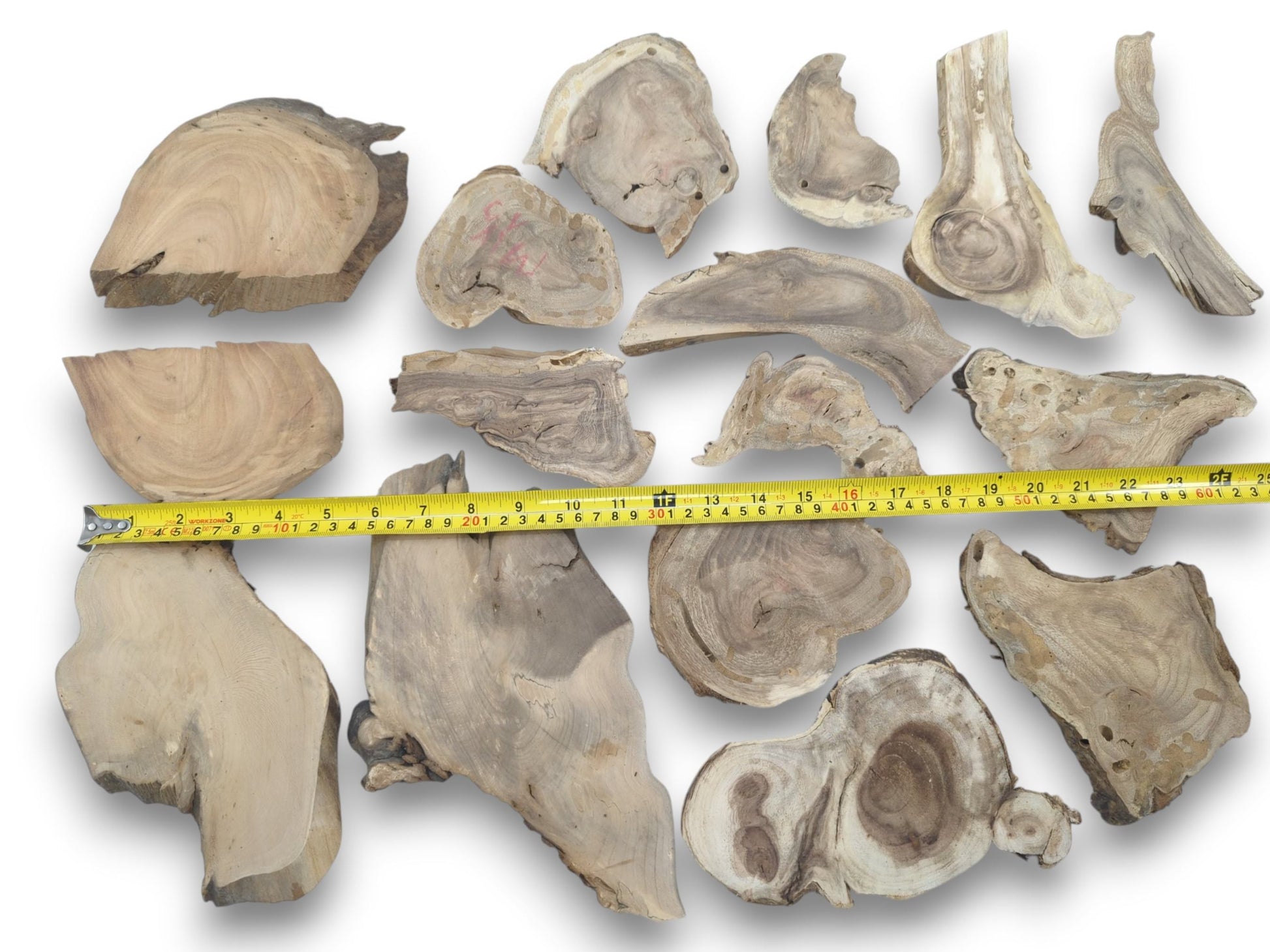 Overhead view of many assorted, irregularly shaped, light-colored wood pieces with prominent grain.
