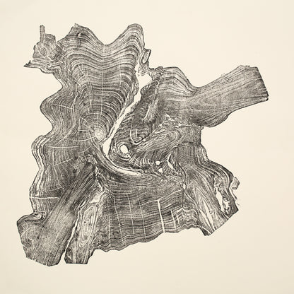 An irregular woodcut monoprint shows a dark impression of tree rings and wood textures on cream paper.