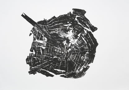 Irregular black woodcut print of a tree root slice, showing a branch extension and growth rings.