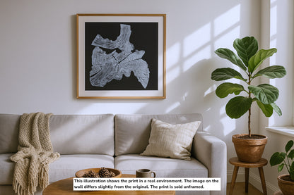A framed monoprint of a white irregular tree root impression on black, displayed above a couch.