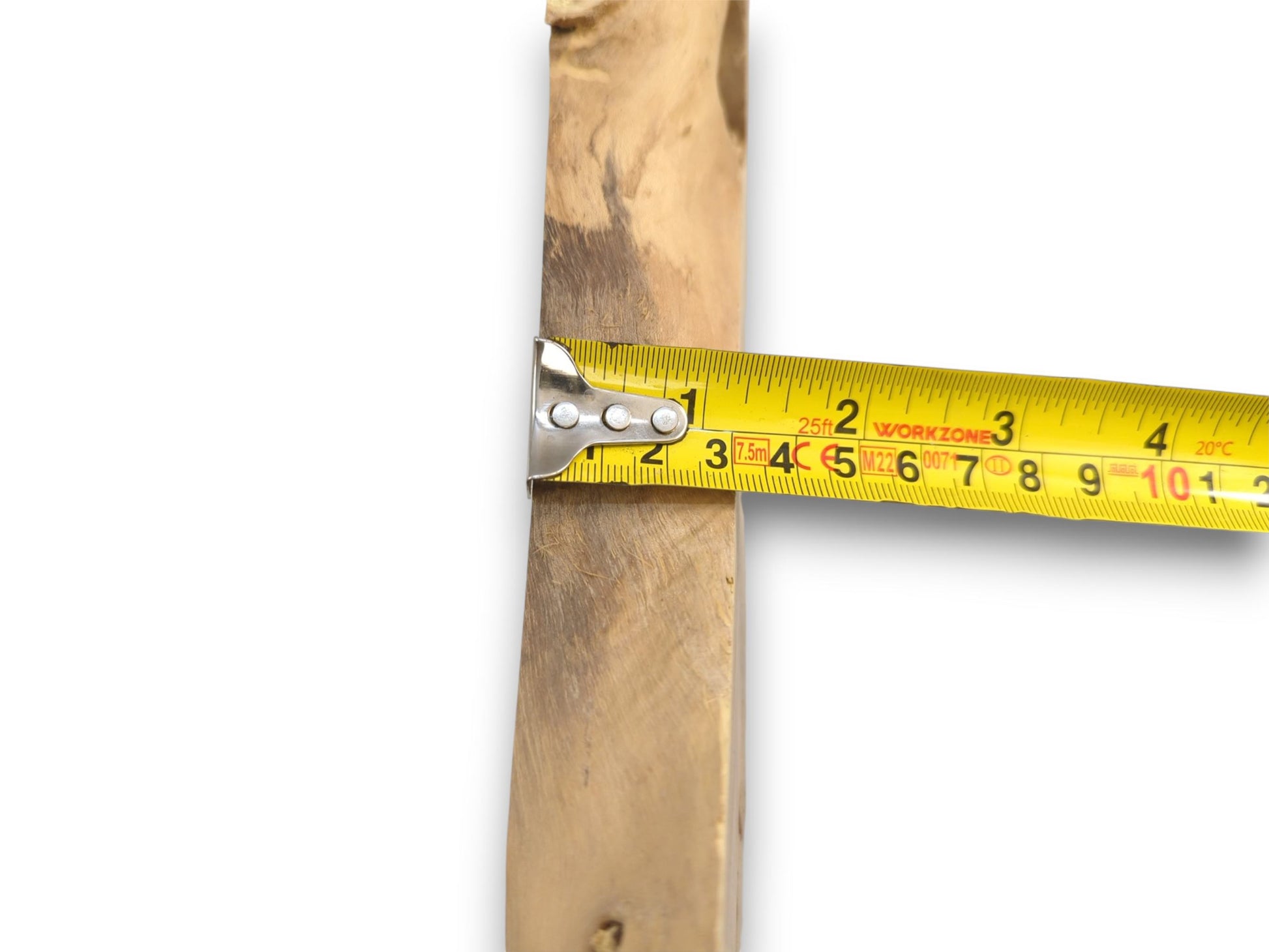 An extended yellow tape measure gauges the thickness of the live edge wood slab's side profile.