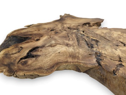 A low-angle view shows a burled timber piece with deep fissures and undulating grain.