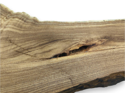 A dark, oblong void splits the fine, parallel grain of a smooth lumber section.