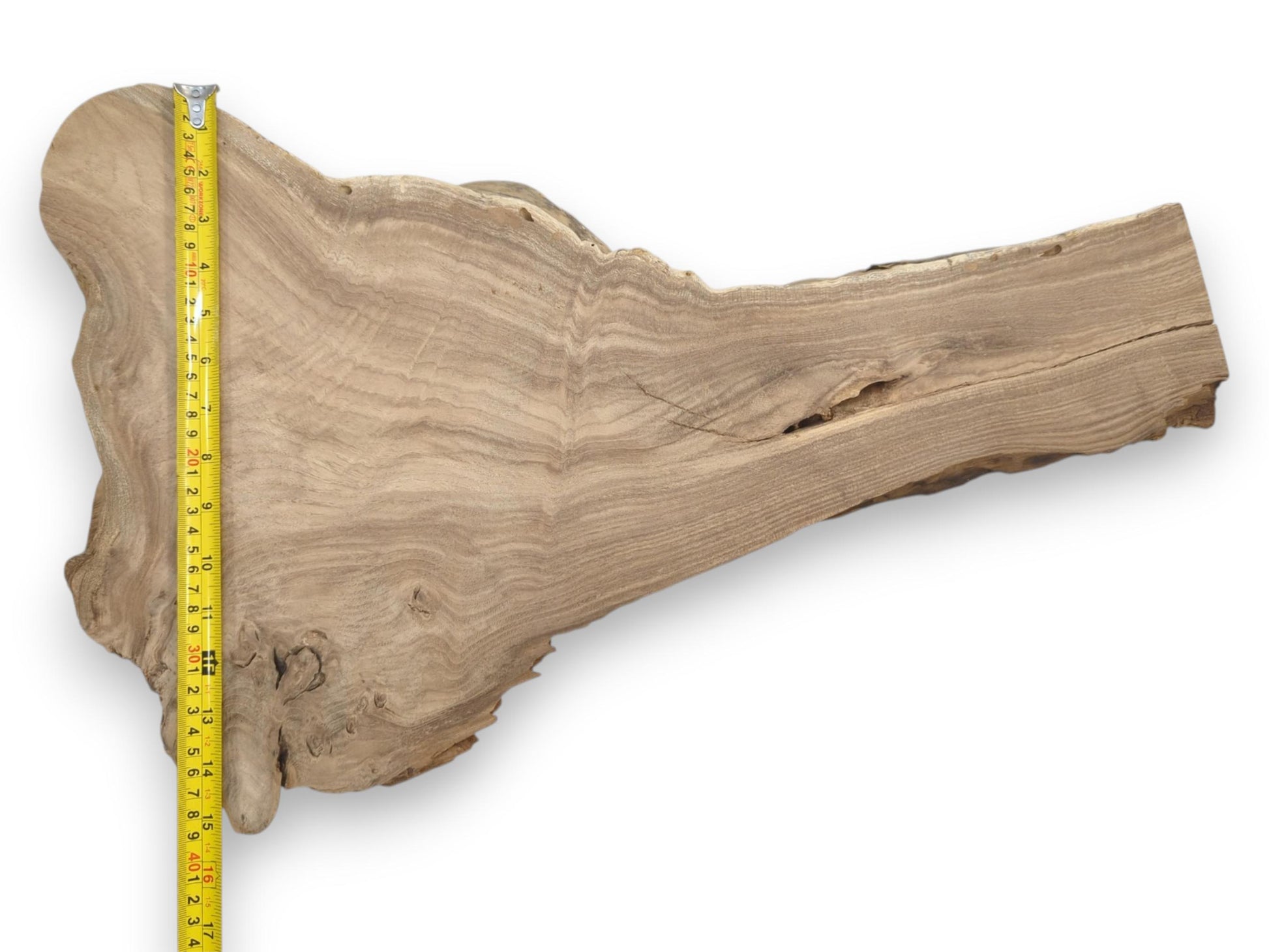 A measuring tape runs along a tapered wood section with a wavy, linear grain.