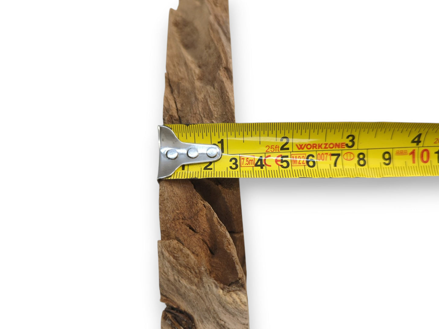A yellow measuring tape's metal hook grips the coarse, fibrous edge of a wood plank.
