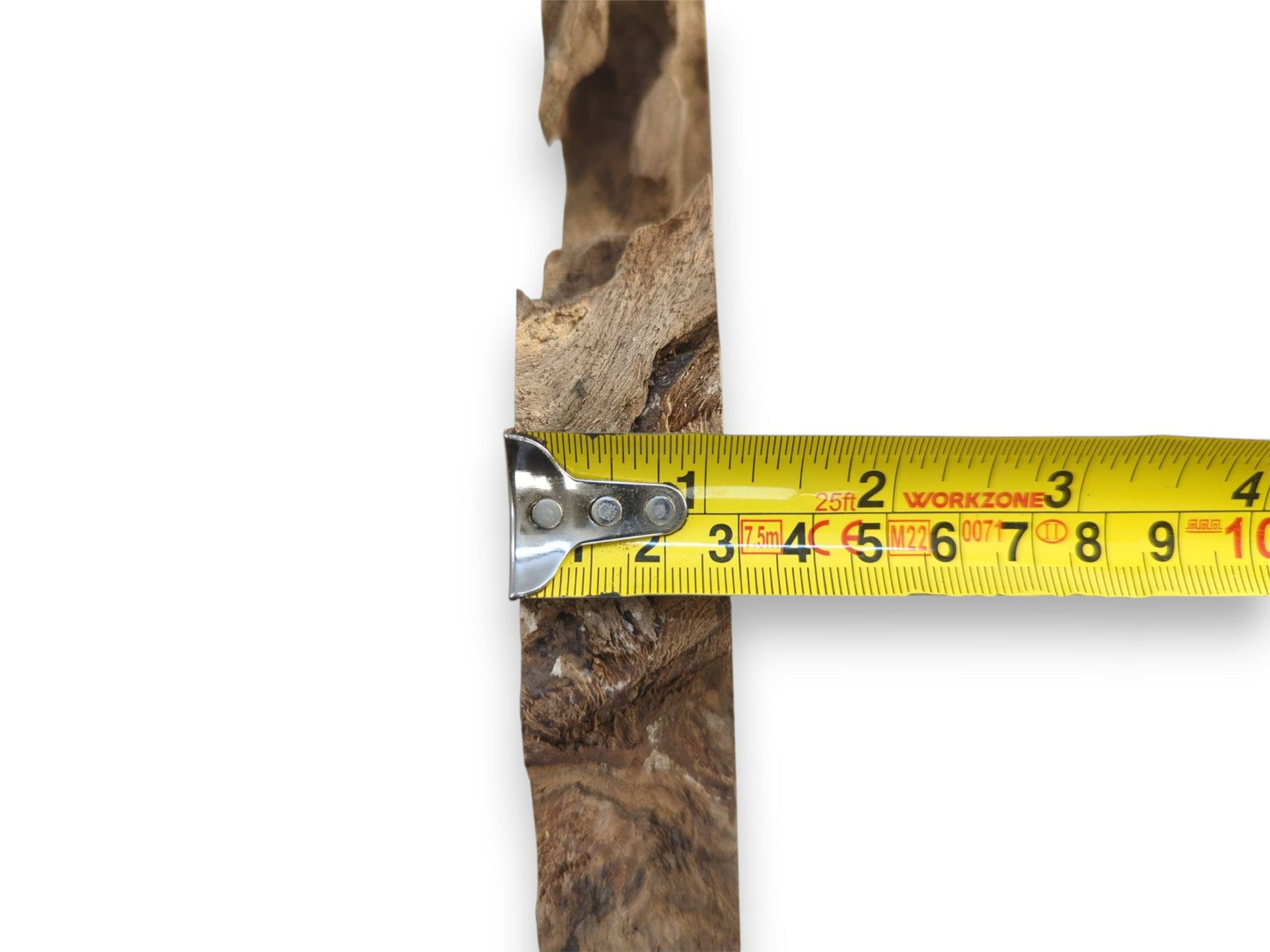 A yellow measuring tape is held across the craggy, uneven surface of a timber piece.