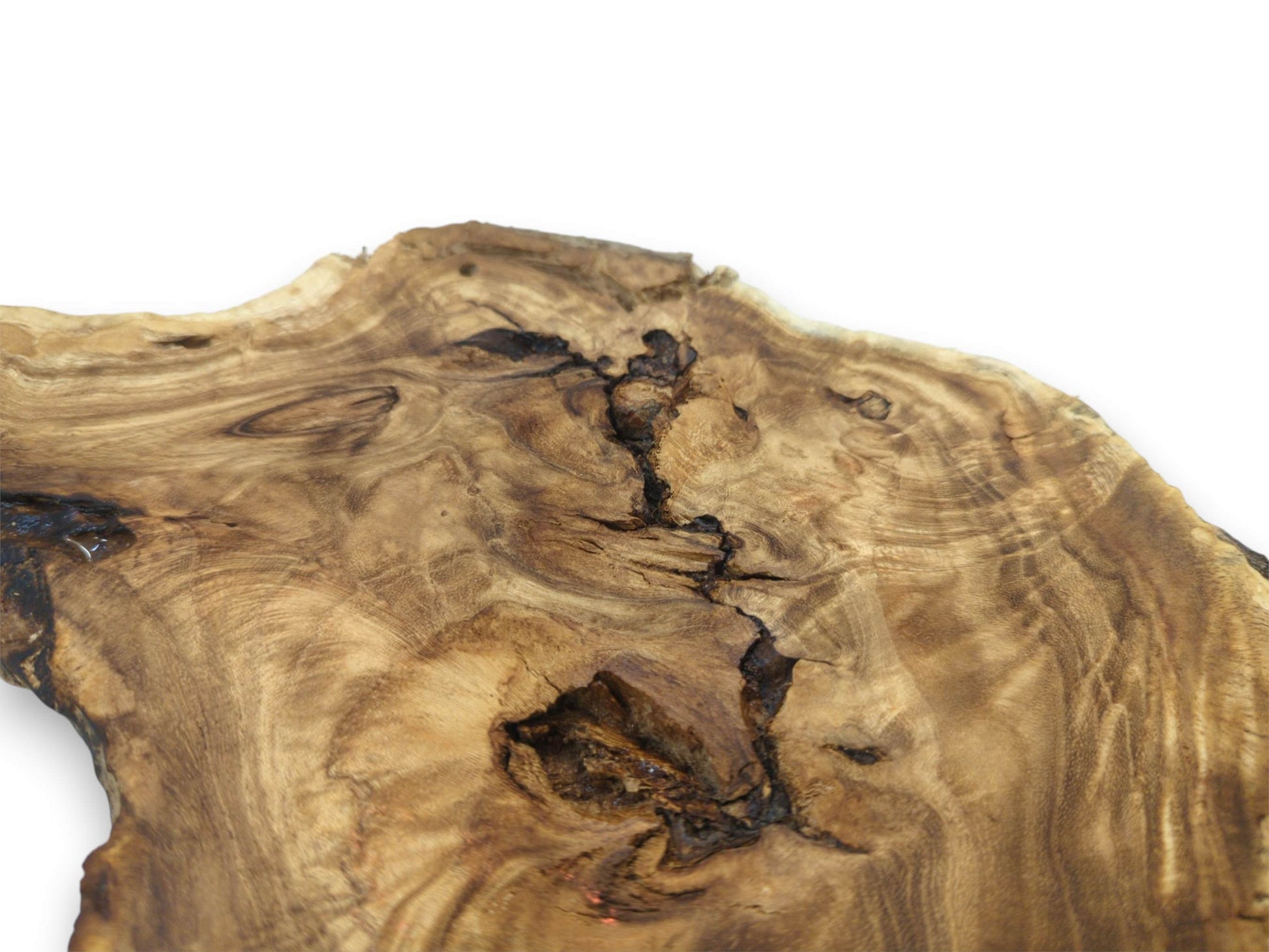 A burled timber section features wild grain patterns flowing around a dark, craggy void.