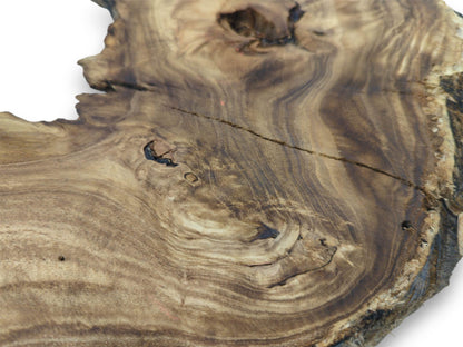 An oblique shot of a wood slab reveals wavy figuring, a thin split, and dark knots.