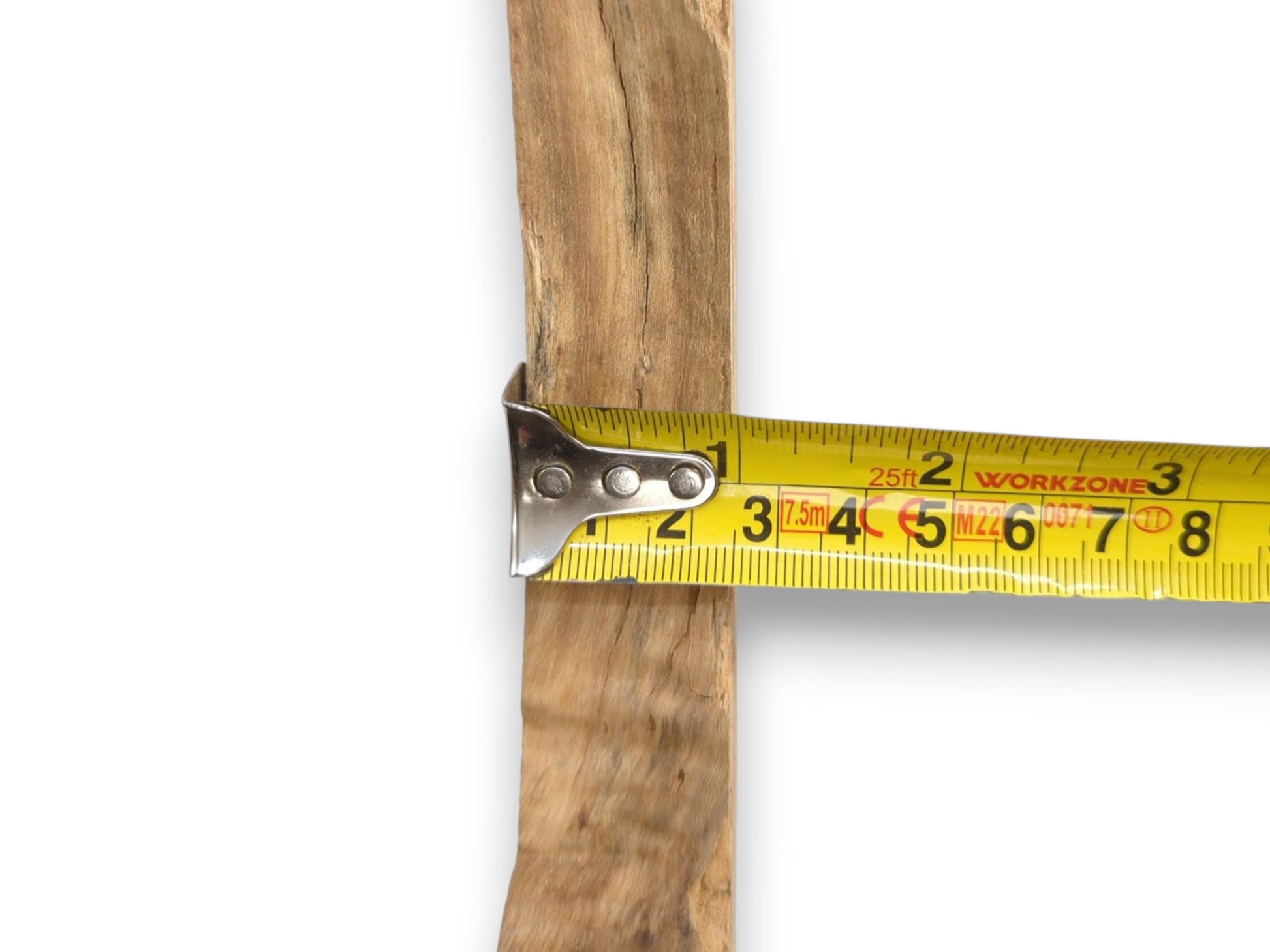 A tape measure's metal hook grips the rough, weathered surface of a vertical wood plank.