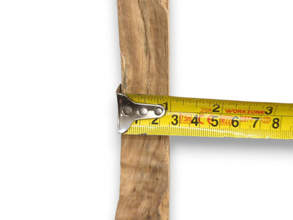A tape measure's metal hook grips the rough, weathered surface of a vertical wood plank.