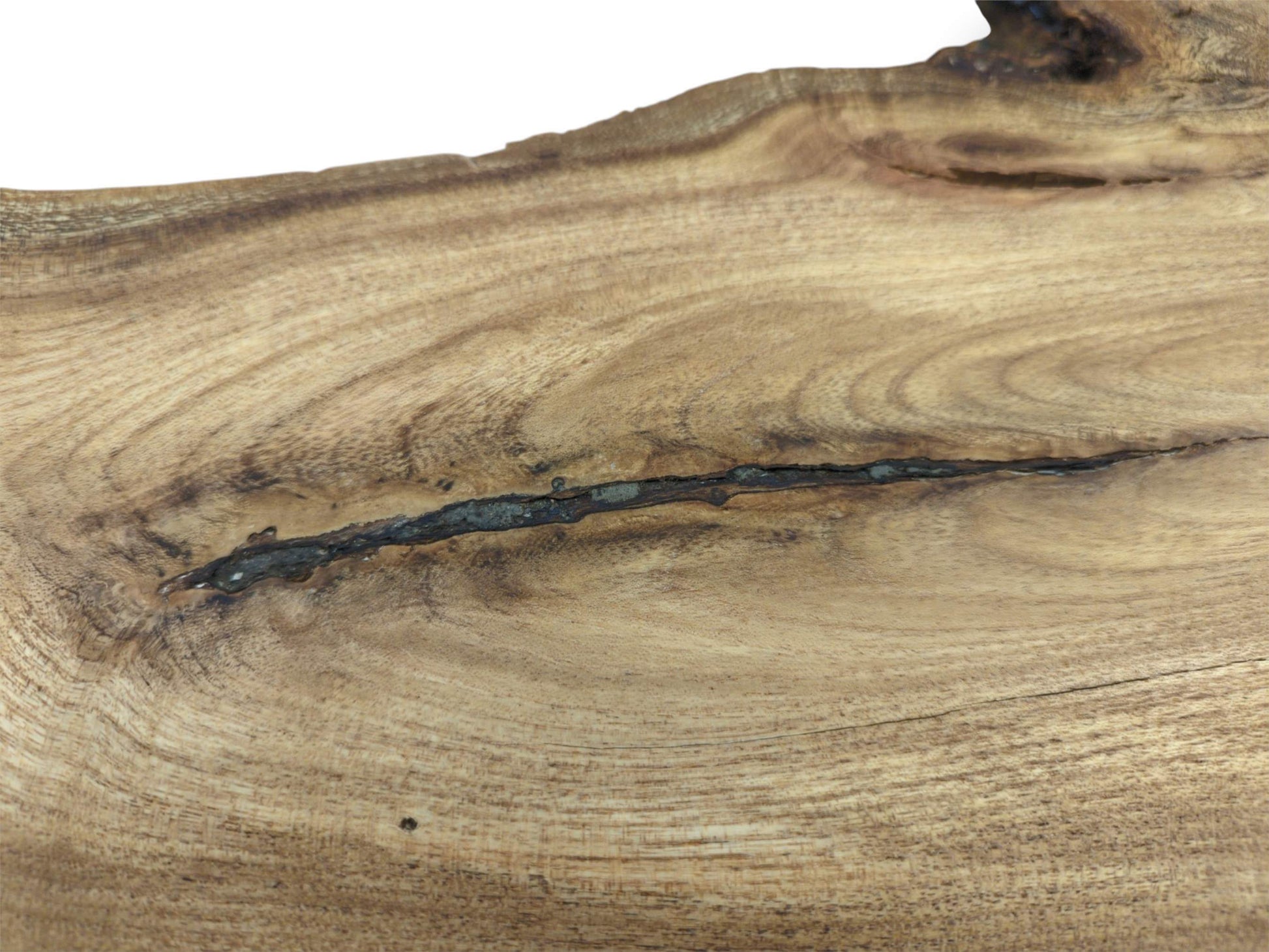 A dark, linear inclusion cuts across the undulating surface of a light-brown wooden board.