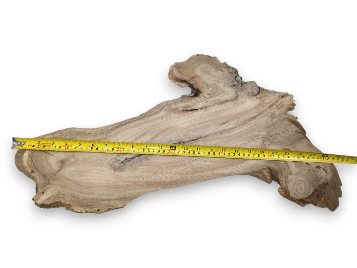 A yellow tape measure lays across a long, natural-form timber slab with wavy grain.
