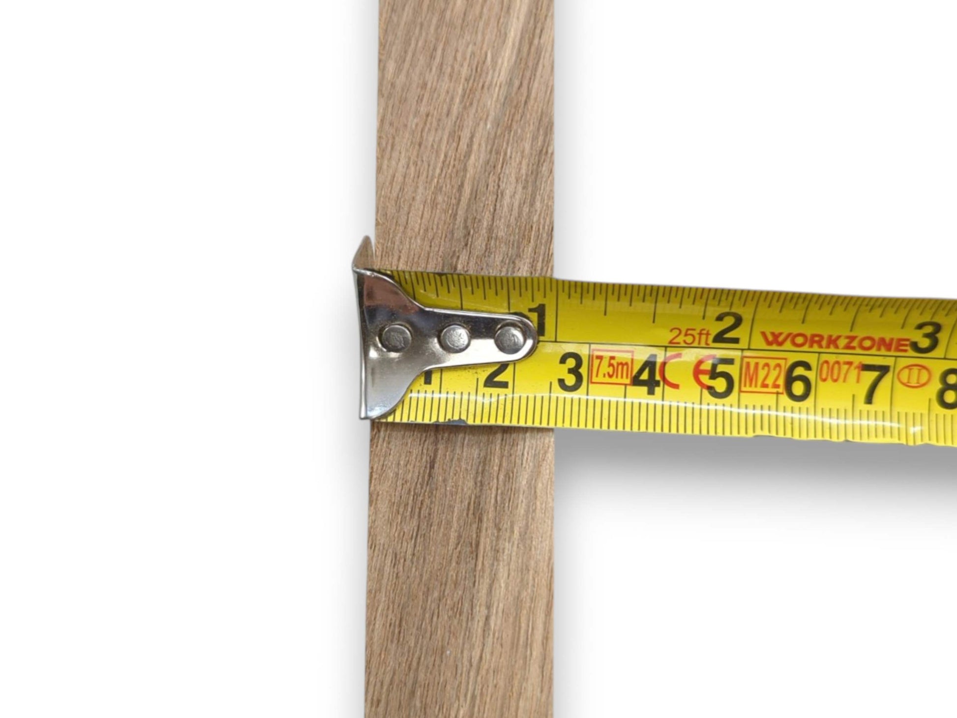 A close-up shows a yellow tape measure determining the width of a straight-grained lumber piece.