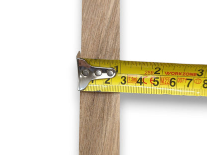 A close-up shows a yellow tape measure determining the width of a straight-grained lumber piece.