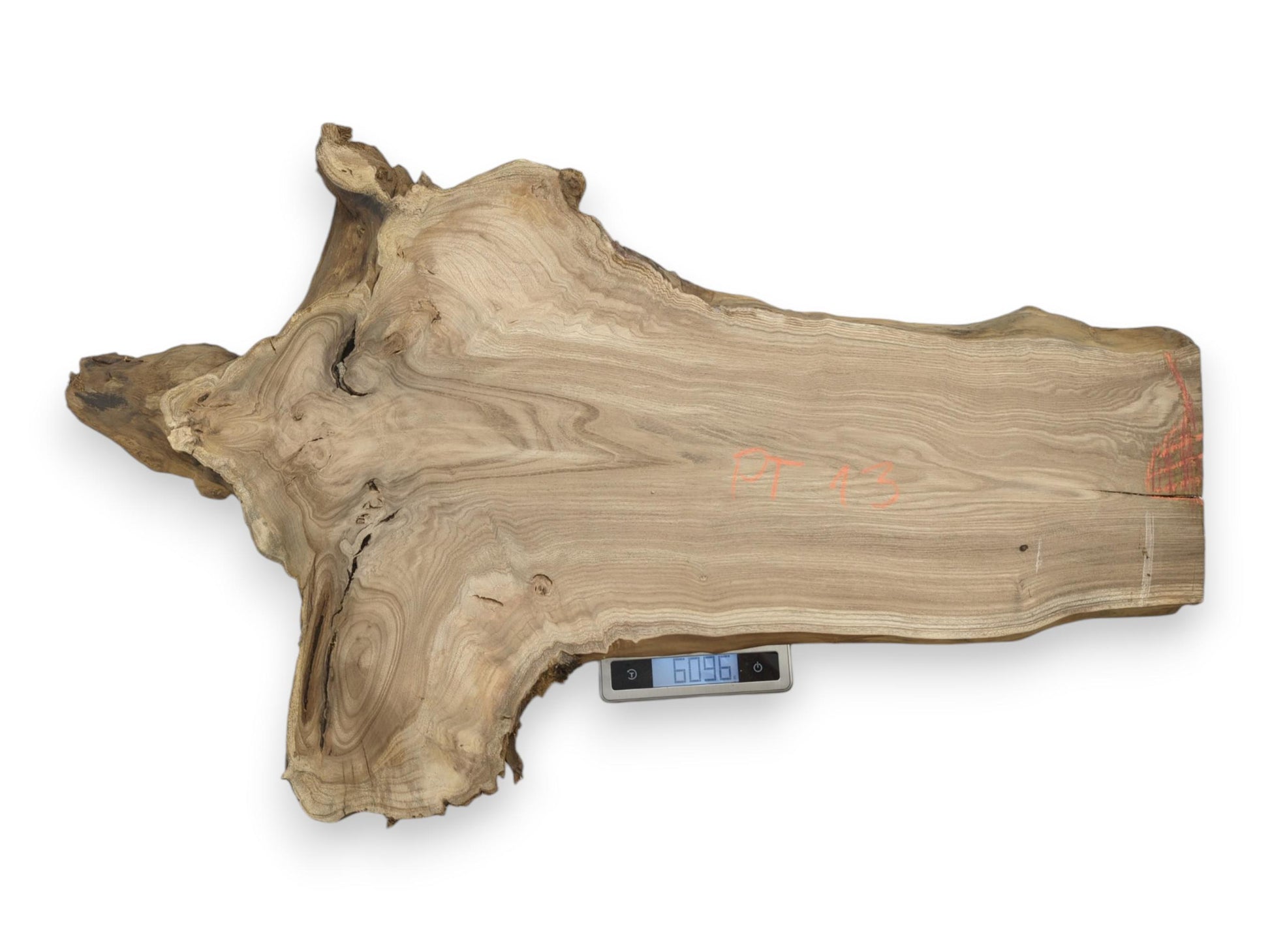 From above, a wide woodcut with orange markings and swirling grain rests on a scale.