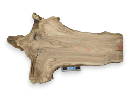 From above, a wide woodcut with orange markings and swirling grain rests on a scale.