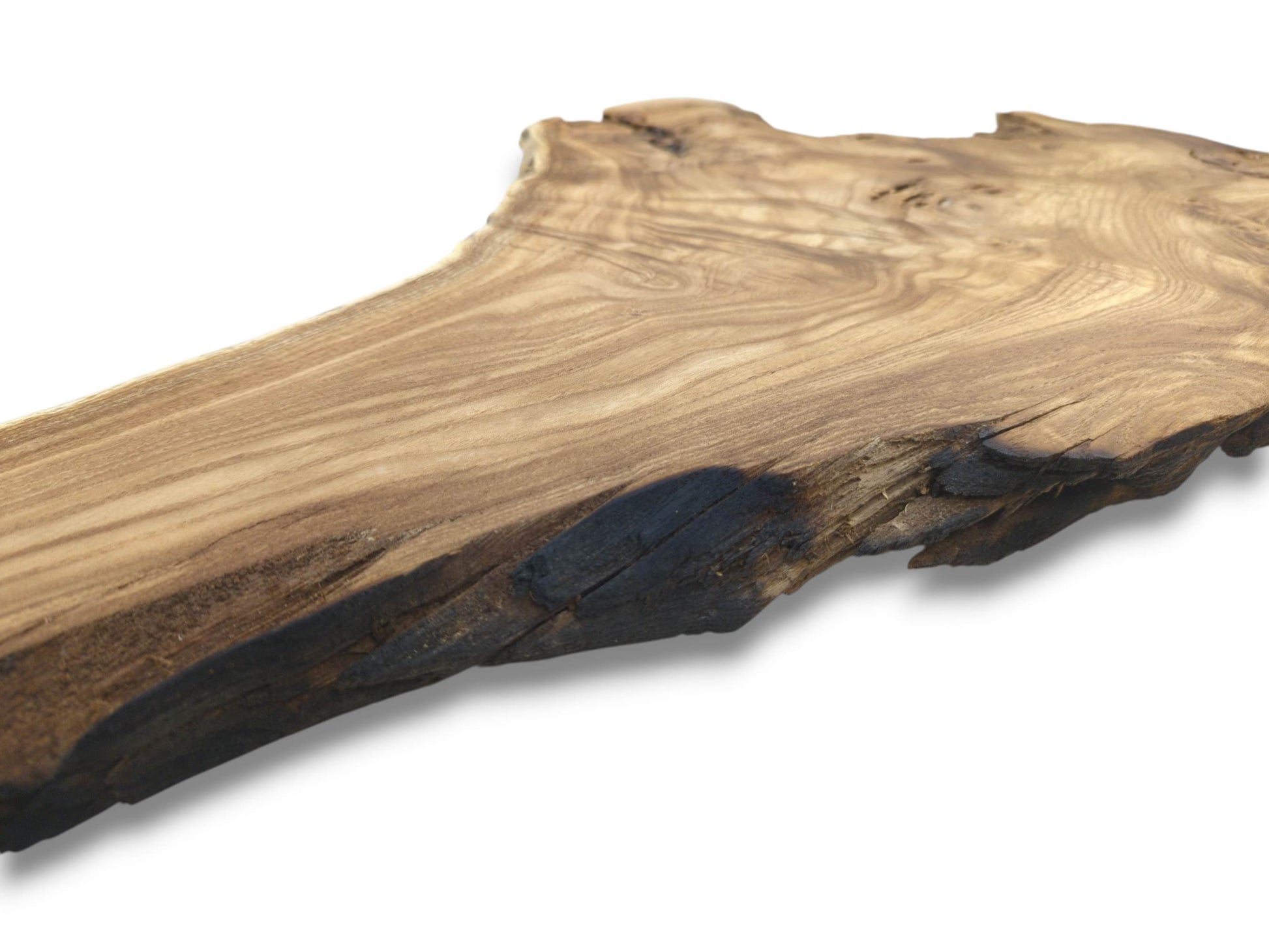 A long timber slab's smooth surface and sweeping grain meet a dark, rugged live edge.