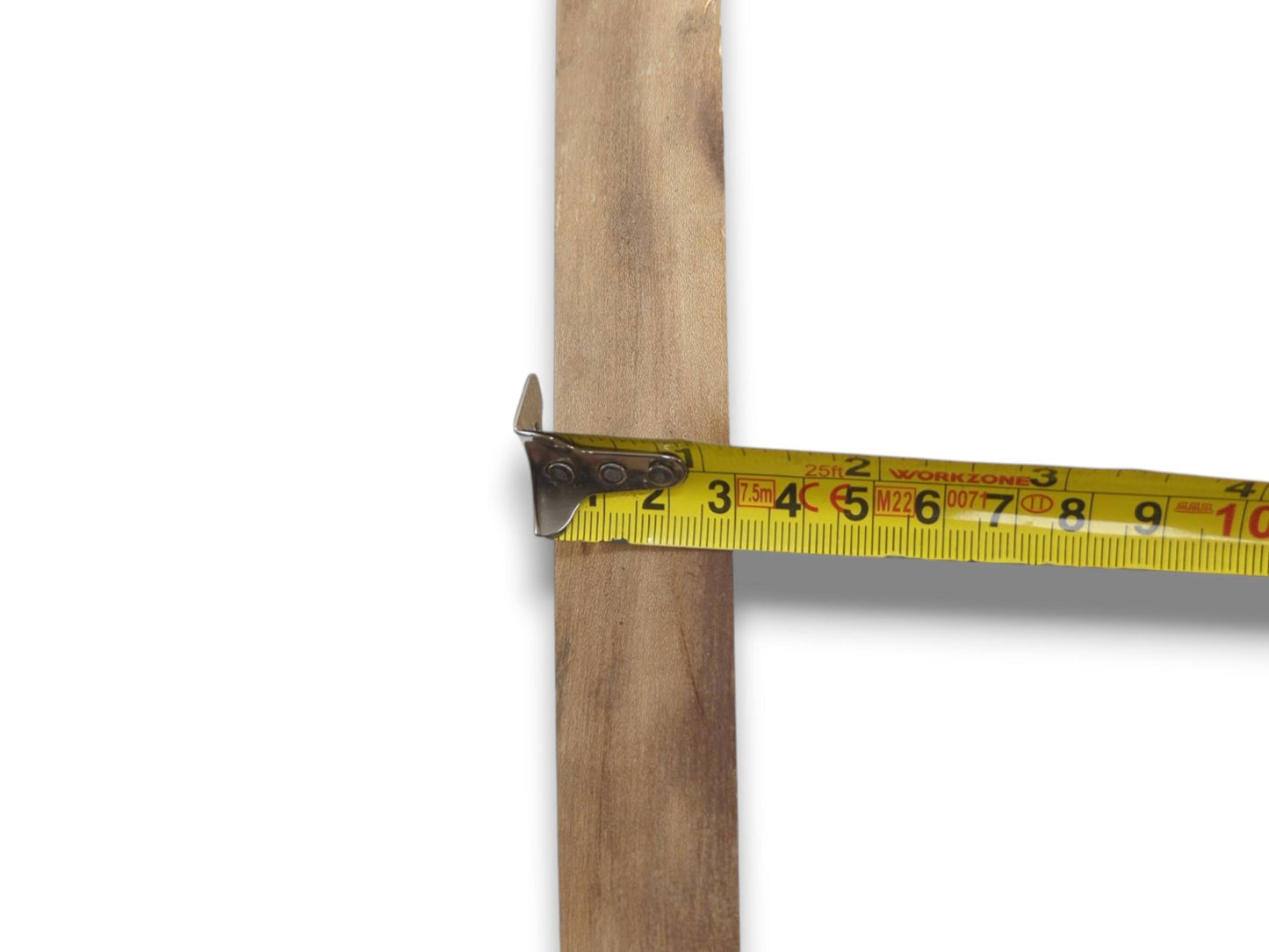 A yellow tape measure hooks the straight edge of a vertical, light-grained timber plank.