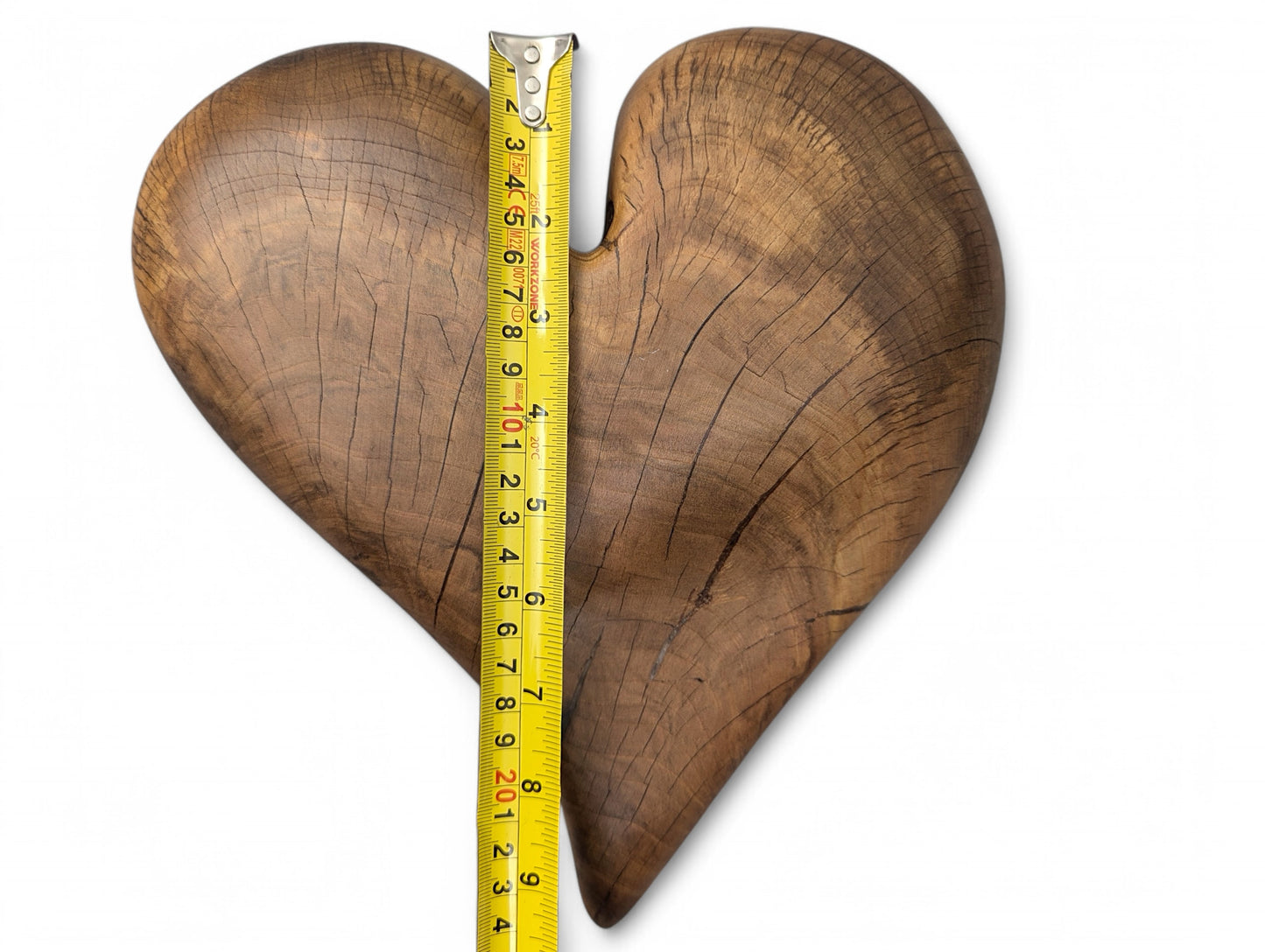 Yellow measuring tape vertically spans a brown heart-shaped hardwood, revealing natural grain, cracks, and 9 inches.